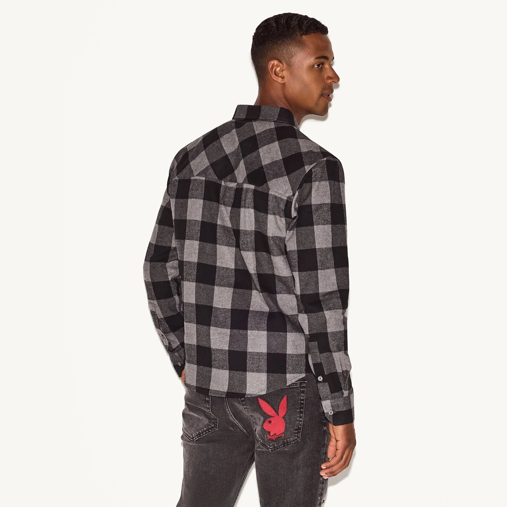 Man modeling black and gray plaid flannel shirt with long sleeves and black jeans