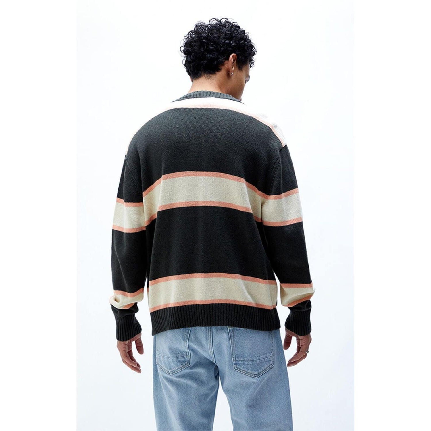 Man wearing black, beige, and tan striped cardigan with blue jeans, back view