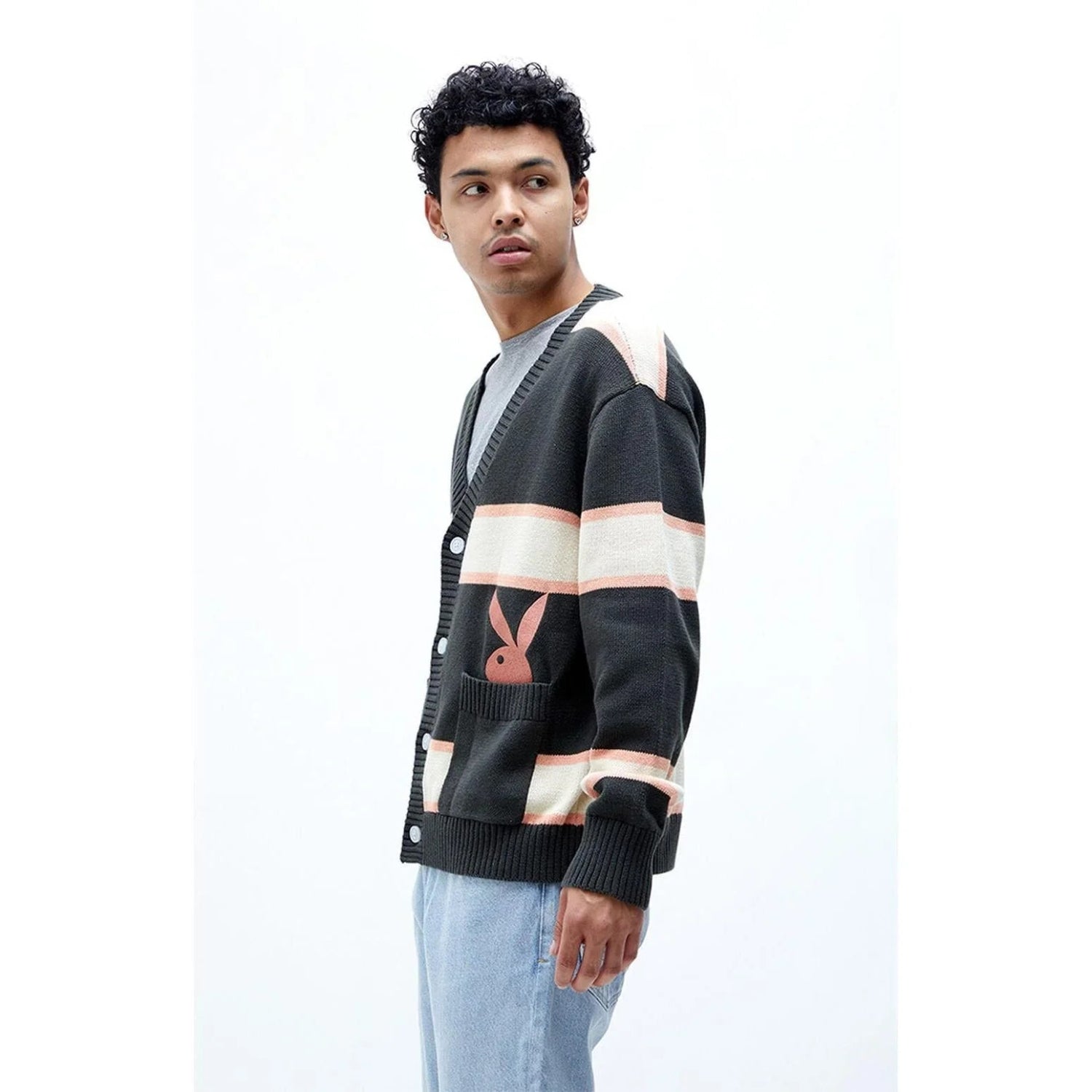 Man wearing striped button-up cardigan with bunny logo and light blue jeans