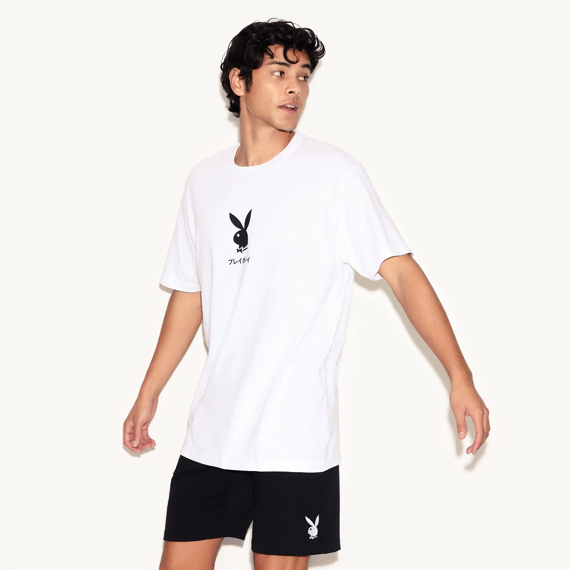 Man wearing black sweat shorts with white rabbit head logo and white graphic t-shirt