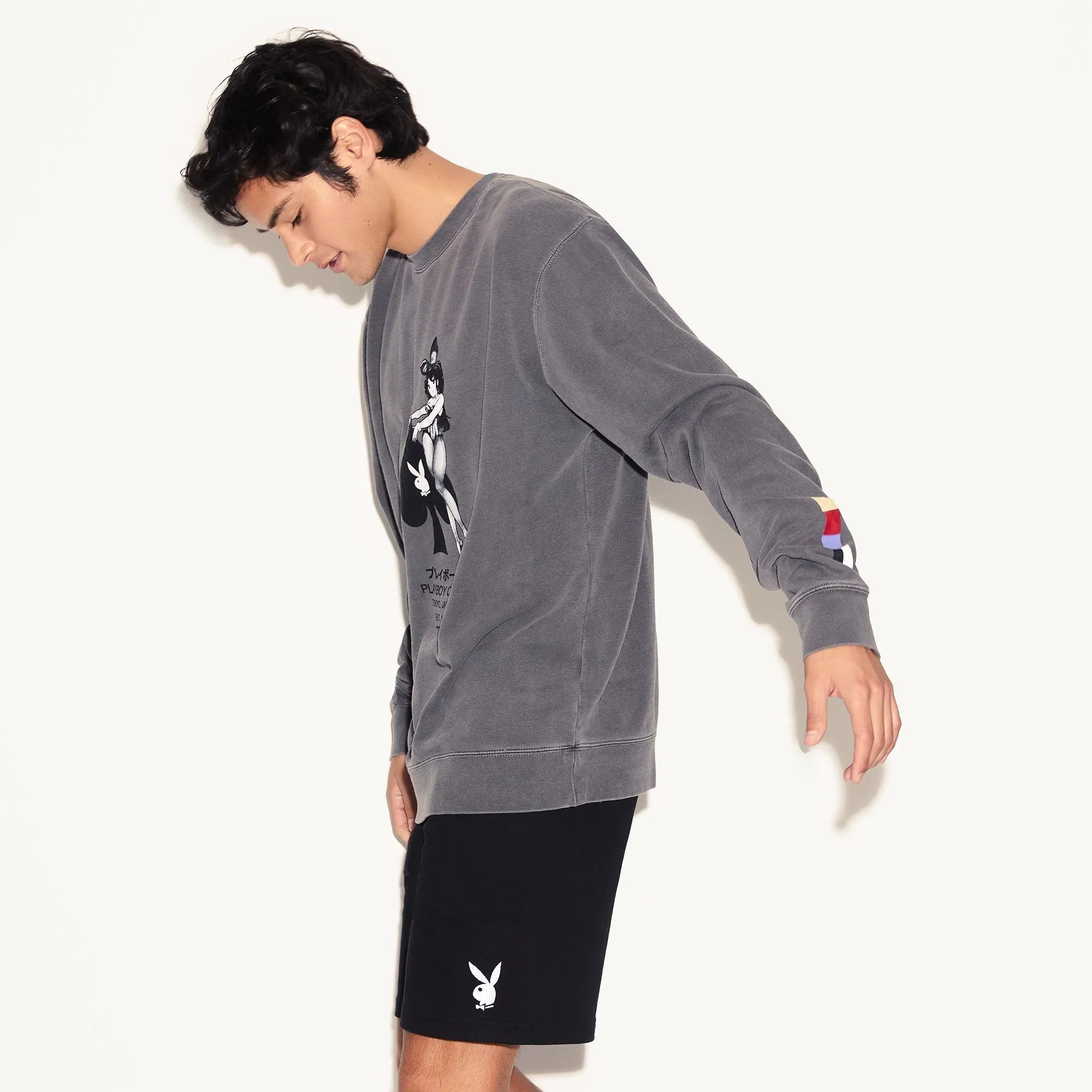 Man wearing black men's sweat shorts with rabbit head logo and a grey graphic sweatshirt