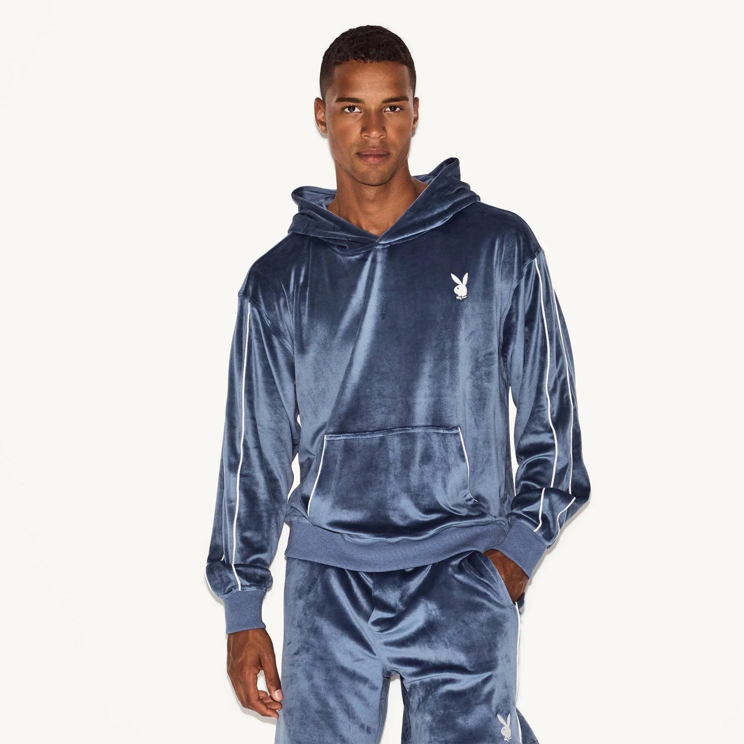 Man wearing blue velour hoodie with white bunny logo and matching pants