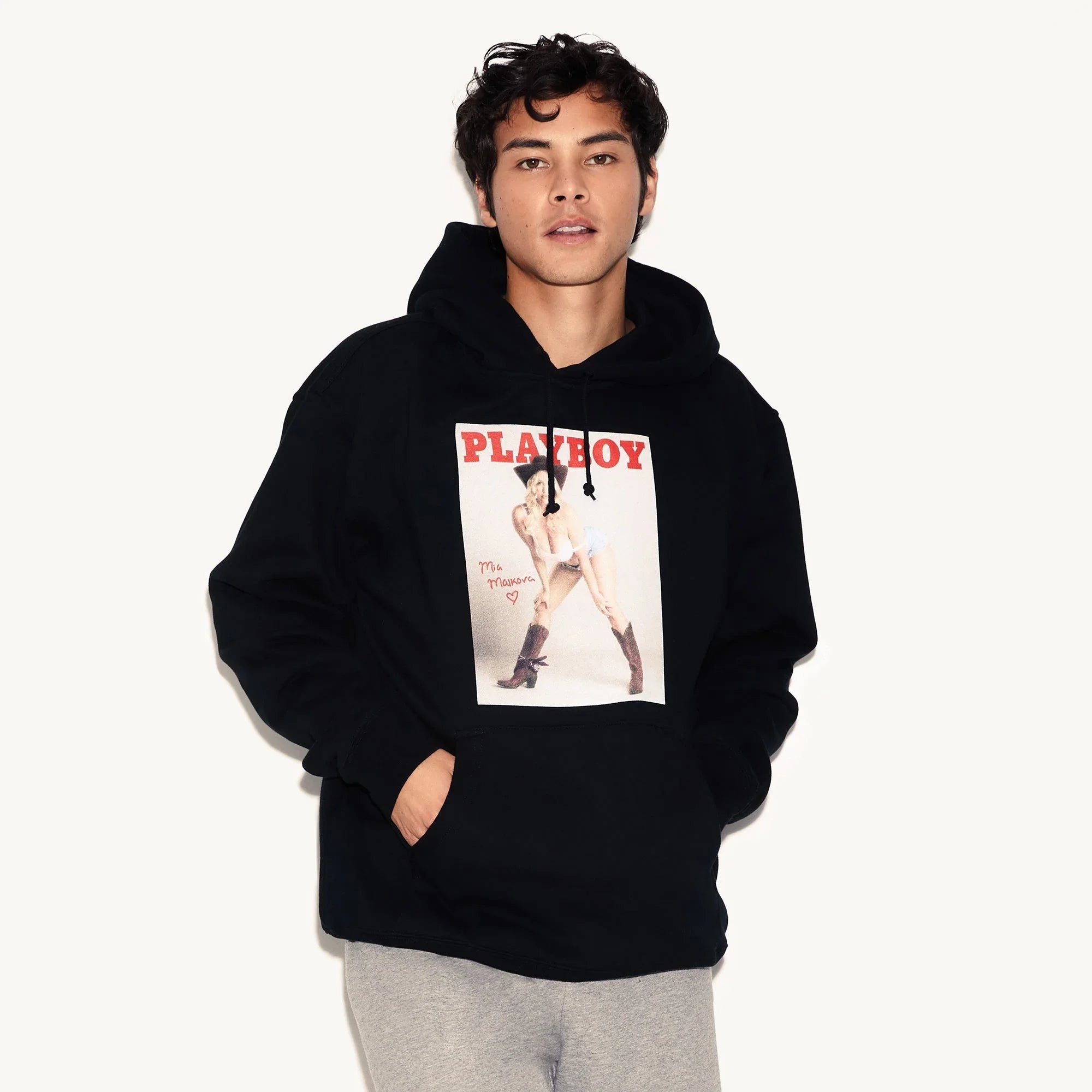 Man wearing black hoodie with vintage magazine cover graphic and bold red text on front
