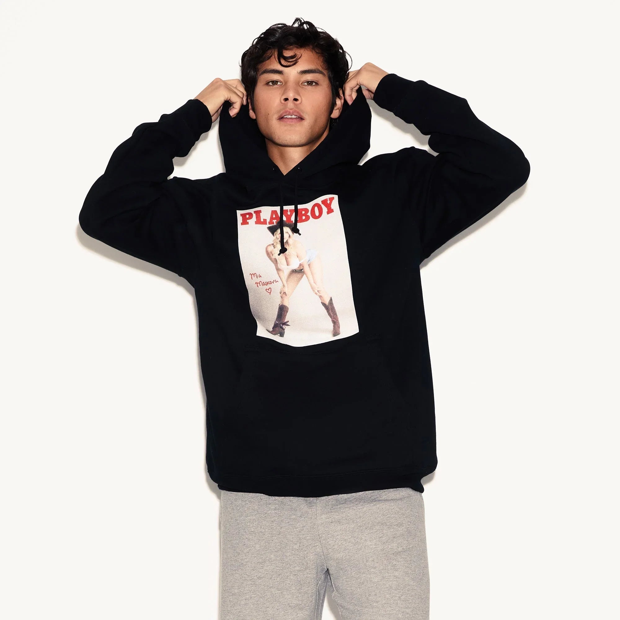 Man wearing black hoodie with magazine cover graphic, pairing it with grey sweatpants.