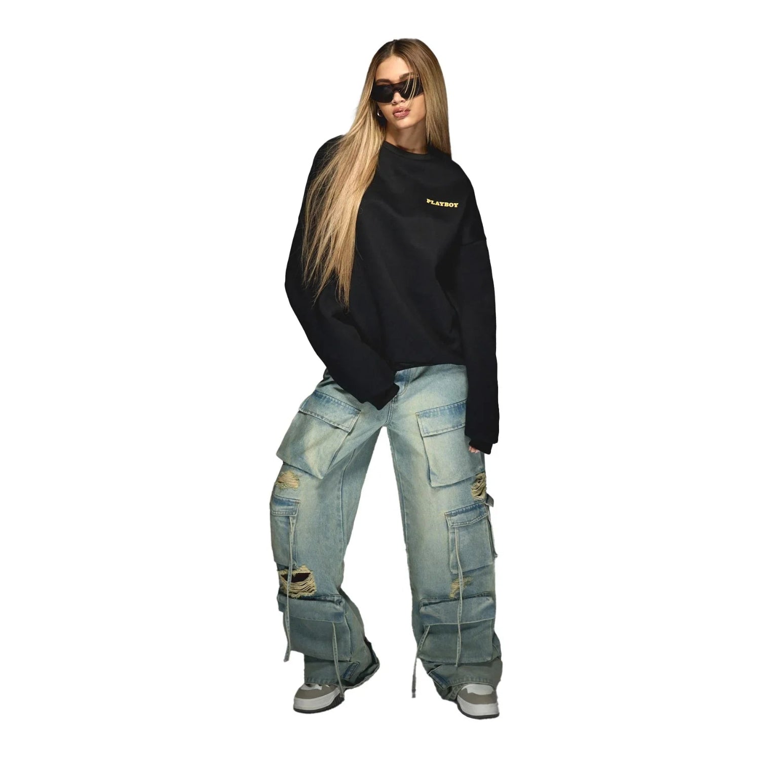 Woman in black Playboy sweatshirt, distressed cargo jeans, and sunglasses on white background