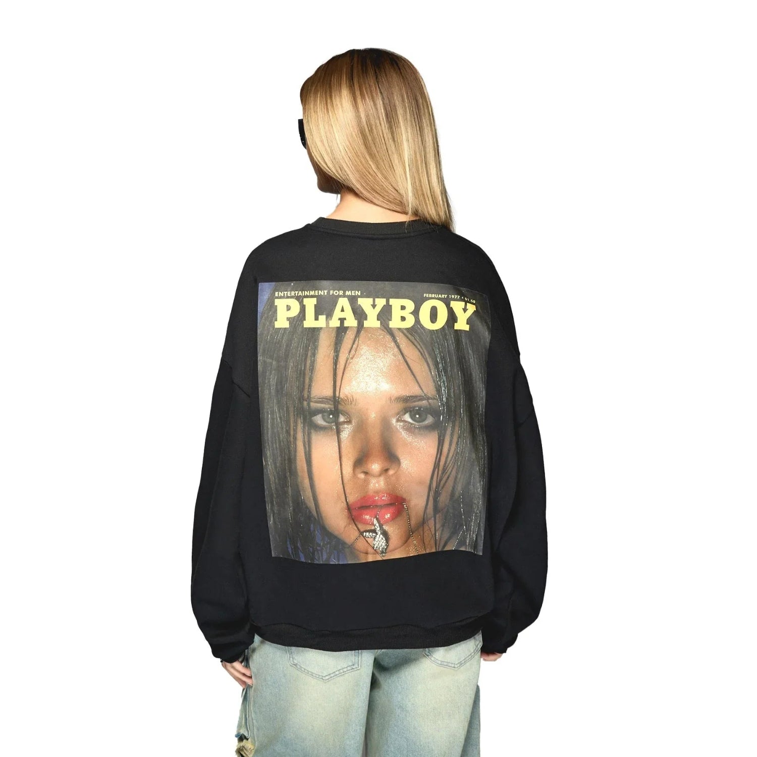 Woman wearing black sweatshirt with vintage magazine cover graphic and light blue jeans