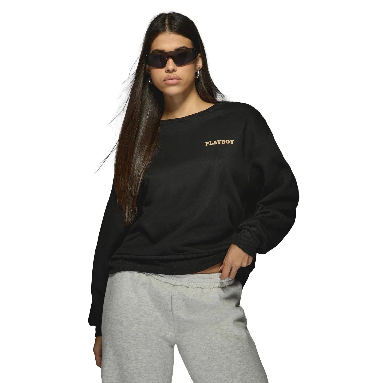 Woman in sunglasses modeling black PLAYBOY sweatshirt and grey sweatpants on white background.