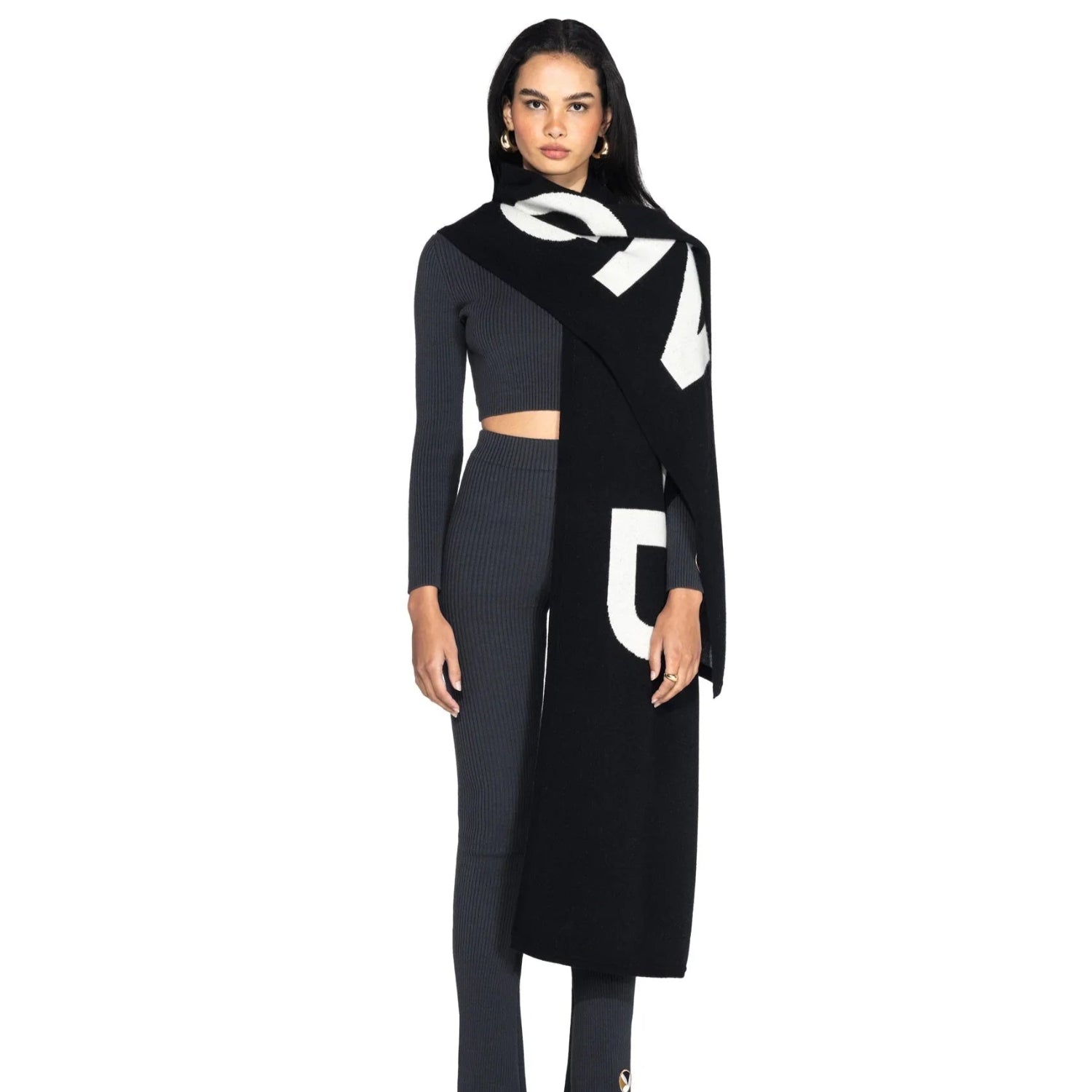 Woman modeling a black and white cashmere scarf over a ribbed gray crop top and pants
