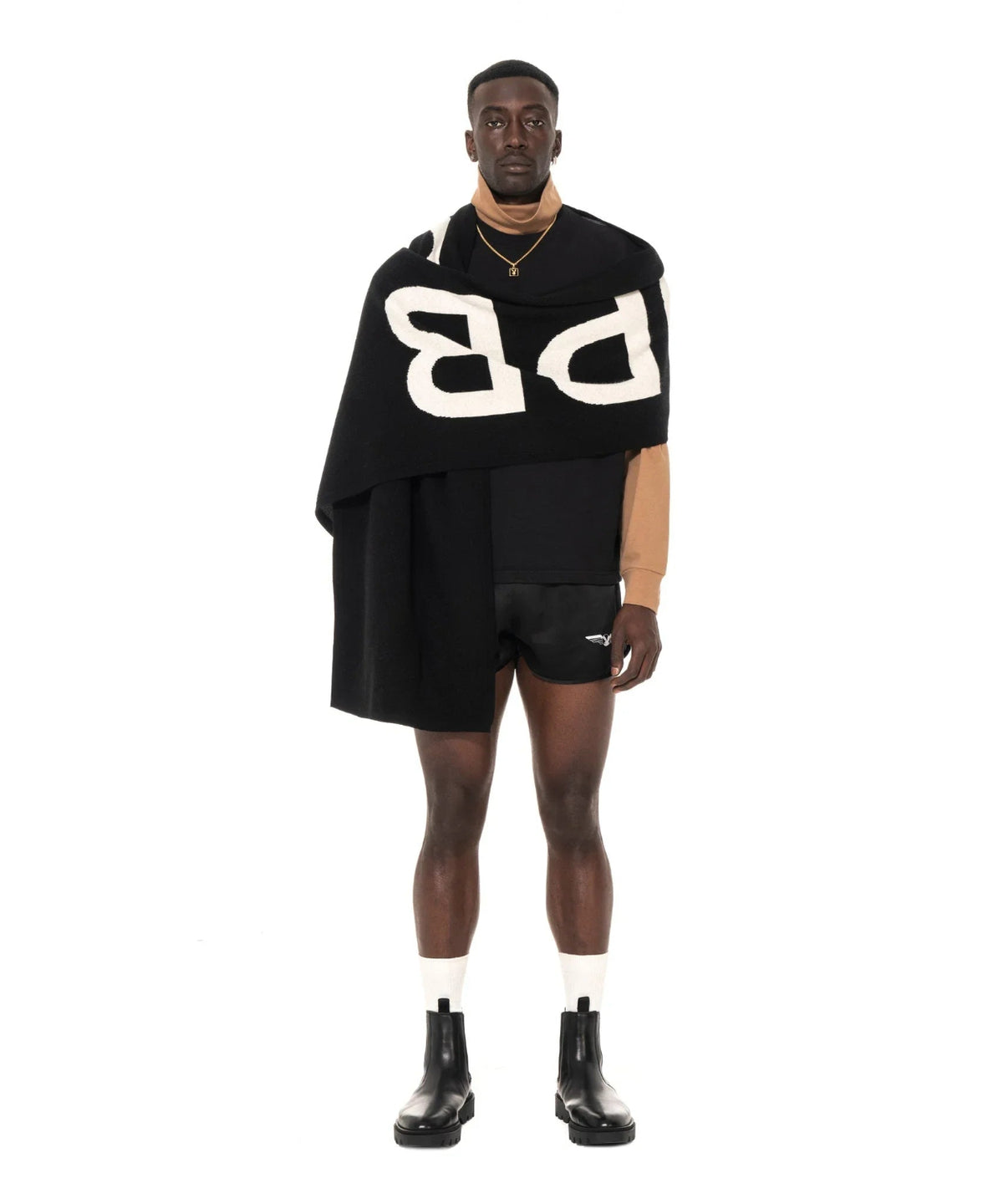 Man modeling a black cashmere scarf with bold white lettering, paired with modern streetwear.