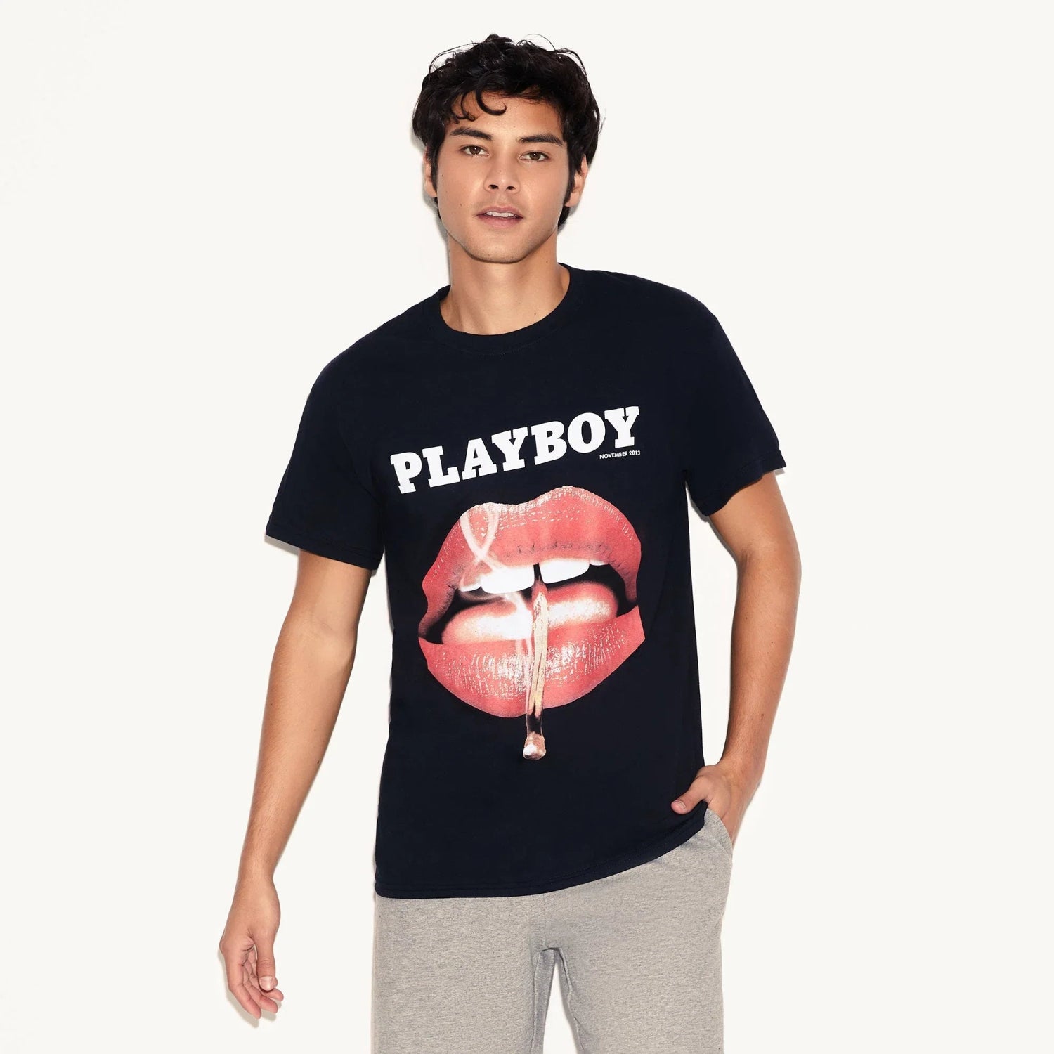 Man wearing black graphic t-shirt with glossy lips and cigarette print, casual fashion style