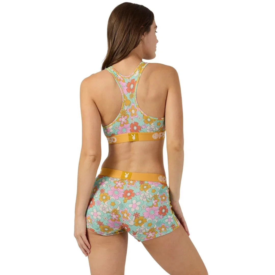 Woman wearing floral print sports bra and shorts set with yellow waistband, back view