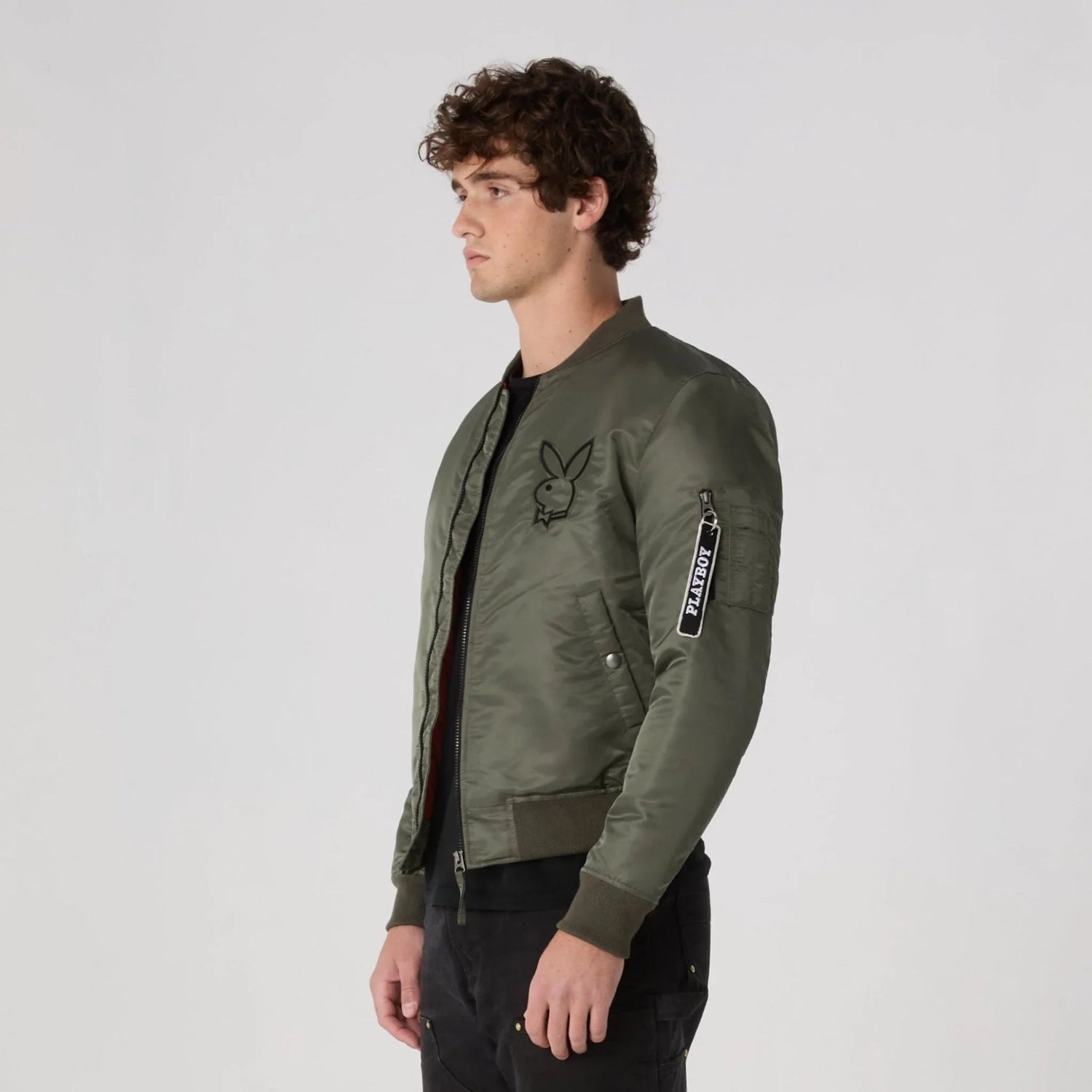 Man wearing khaki green bomber jacket with logo patch and zip pocket on sleeve