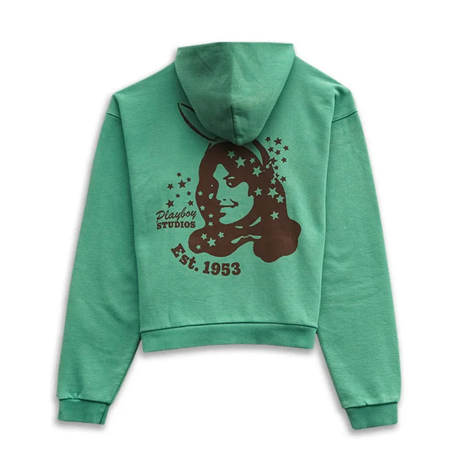 Green hoodie with brown retro graphic of woman's face, stars, and text 'Playboy Studios Est. 1953' on back.