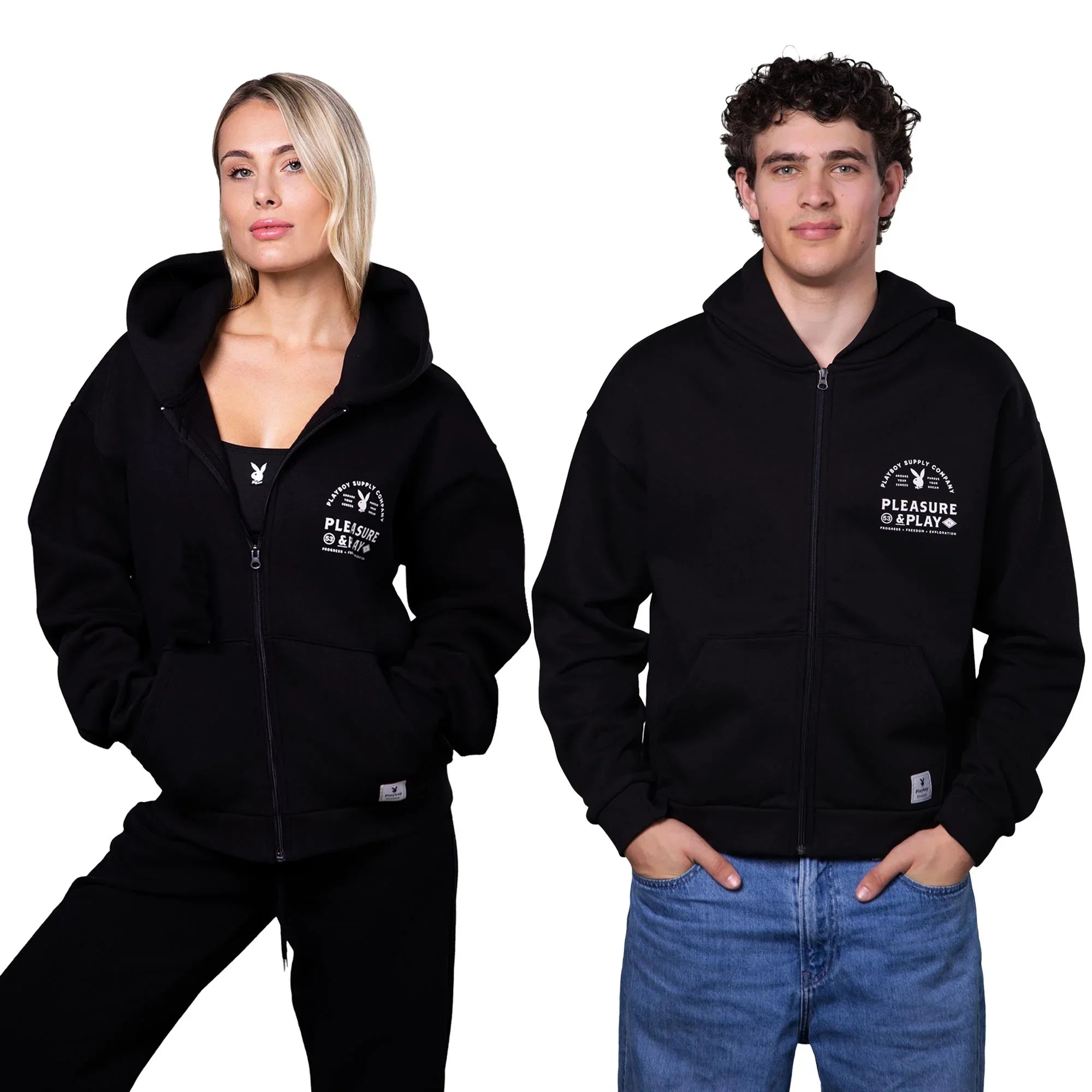 Two models wearing black zip-up hoodies with white 'Pleasure @ Play' chest print and front pockets