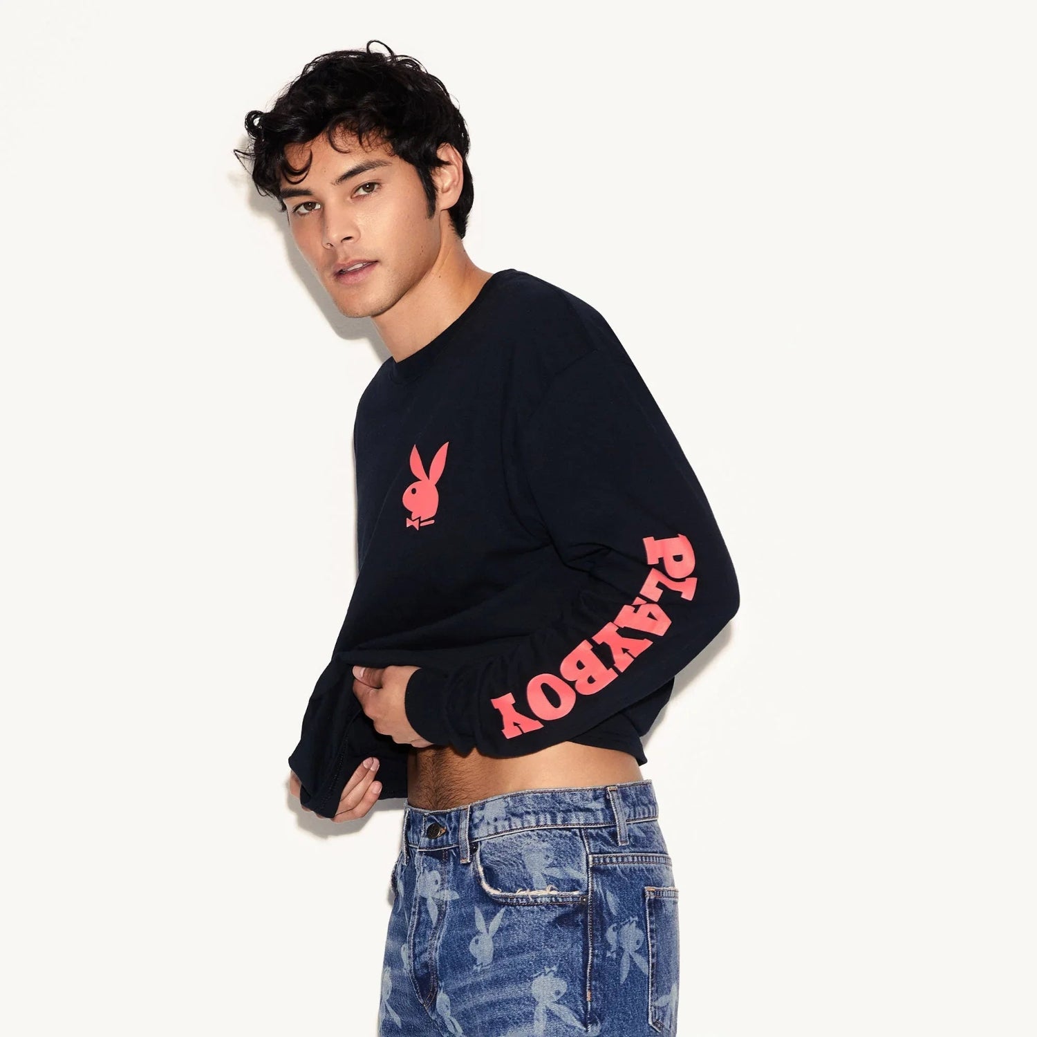 Man wearing black long sleeve shirt with pink rabbit head logo and bold sleeve lettering