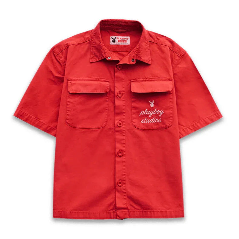 Red short sleeve button-up shirt with front pockets and 'playboy studios' embroidery.