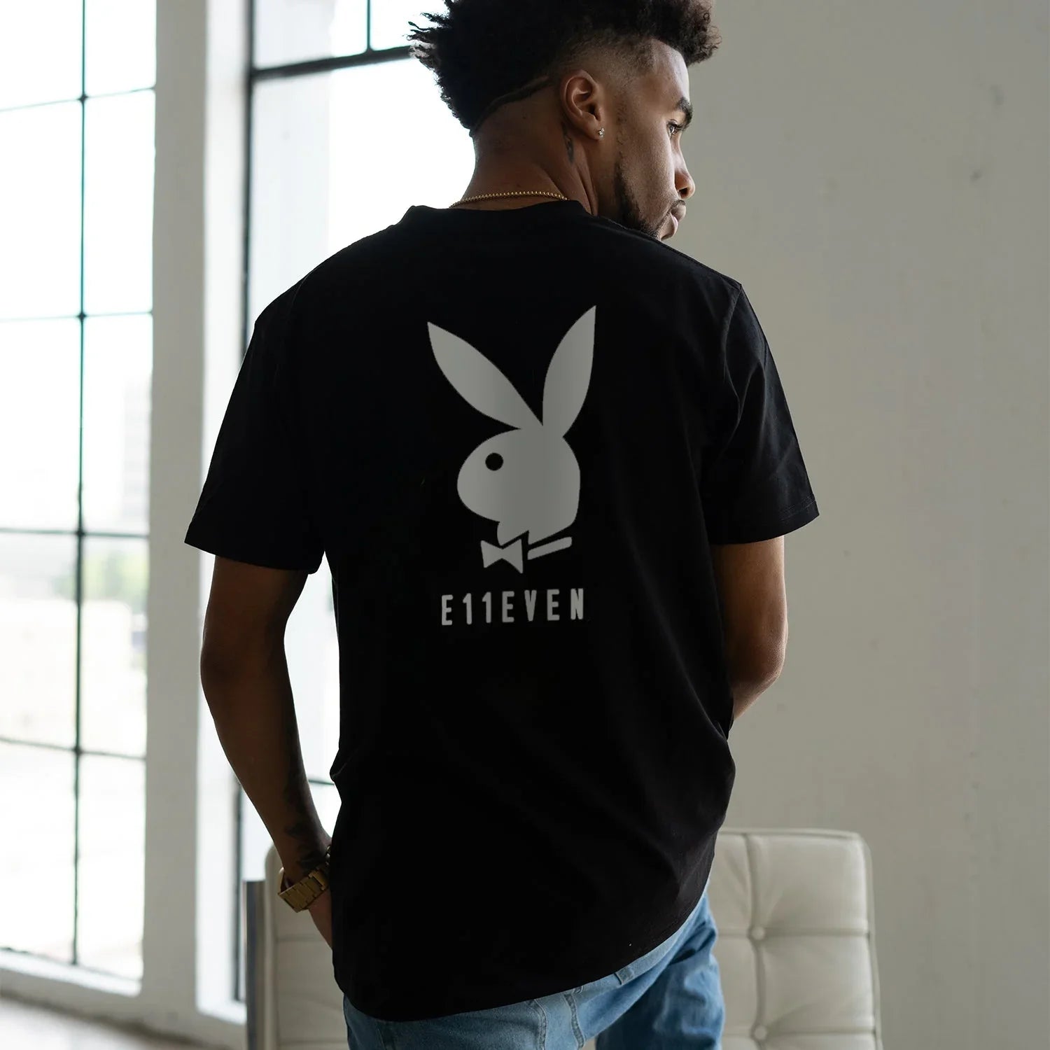 Man wearing black t-shirt with large white bunny logo and E11EVEN text on the back