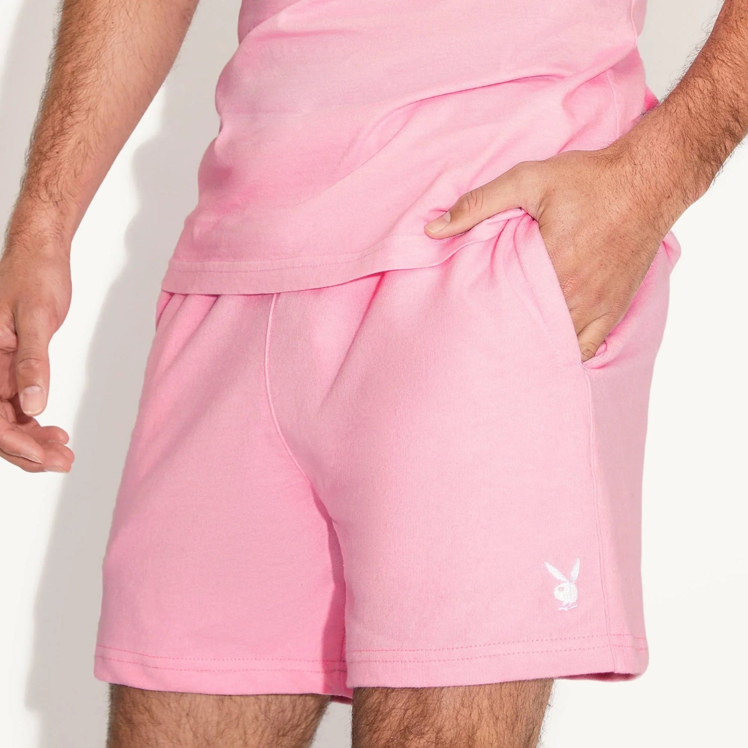 Men's pink sweatshorts with white bunny logo, casual loungewear, hand in pocket