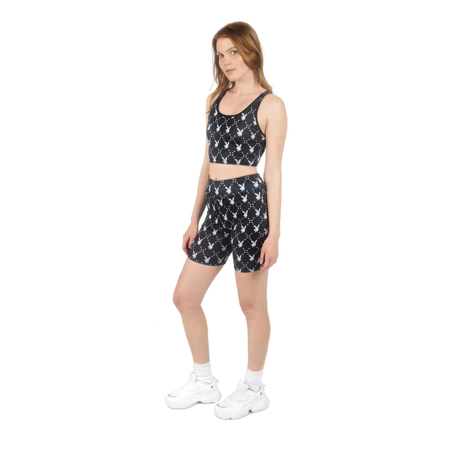 Woman wearing black crop top and biker shorts with white rabbit head print, white sneakers