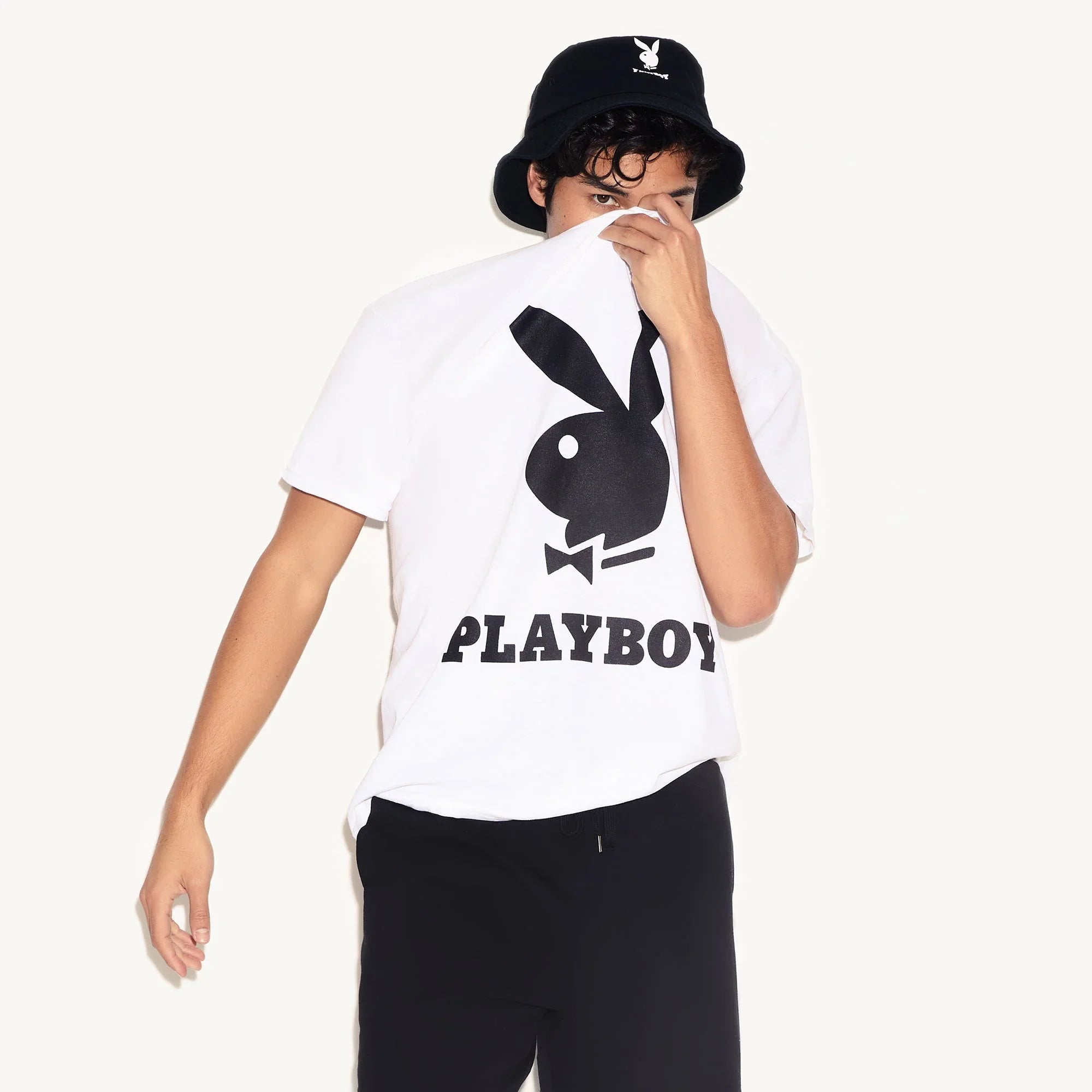 Man wearing black bucket hat with rabbit head logo and white graphic t-shirt