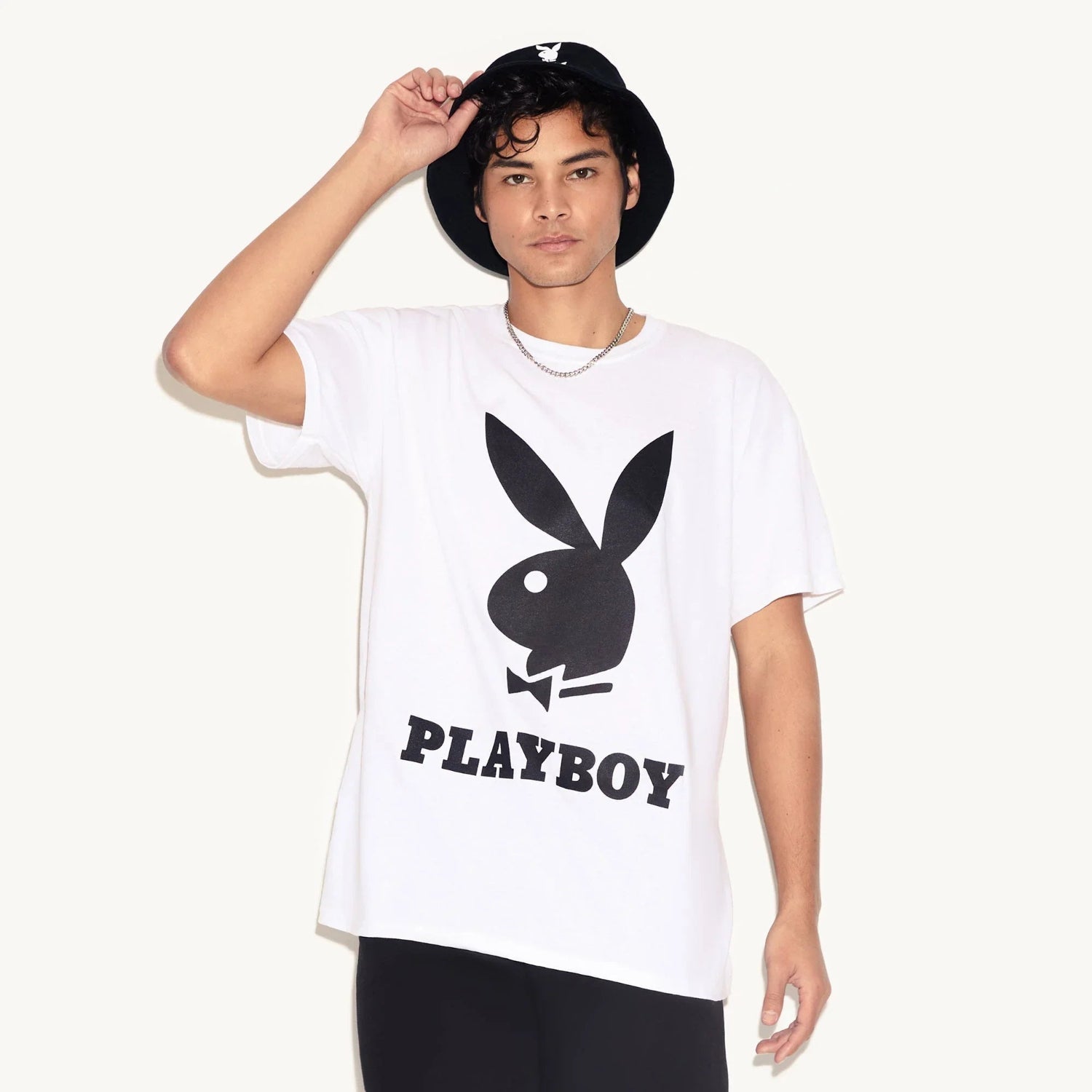 Man wearing black bucket hat with white rabbit head logo and white graphic t-shirt