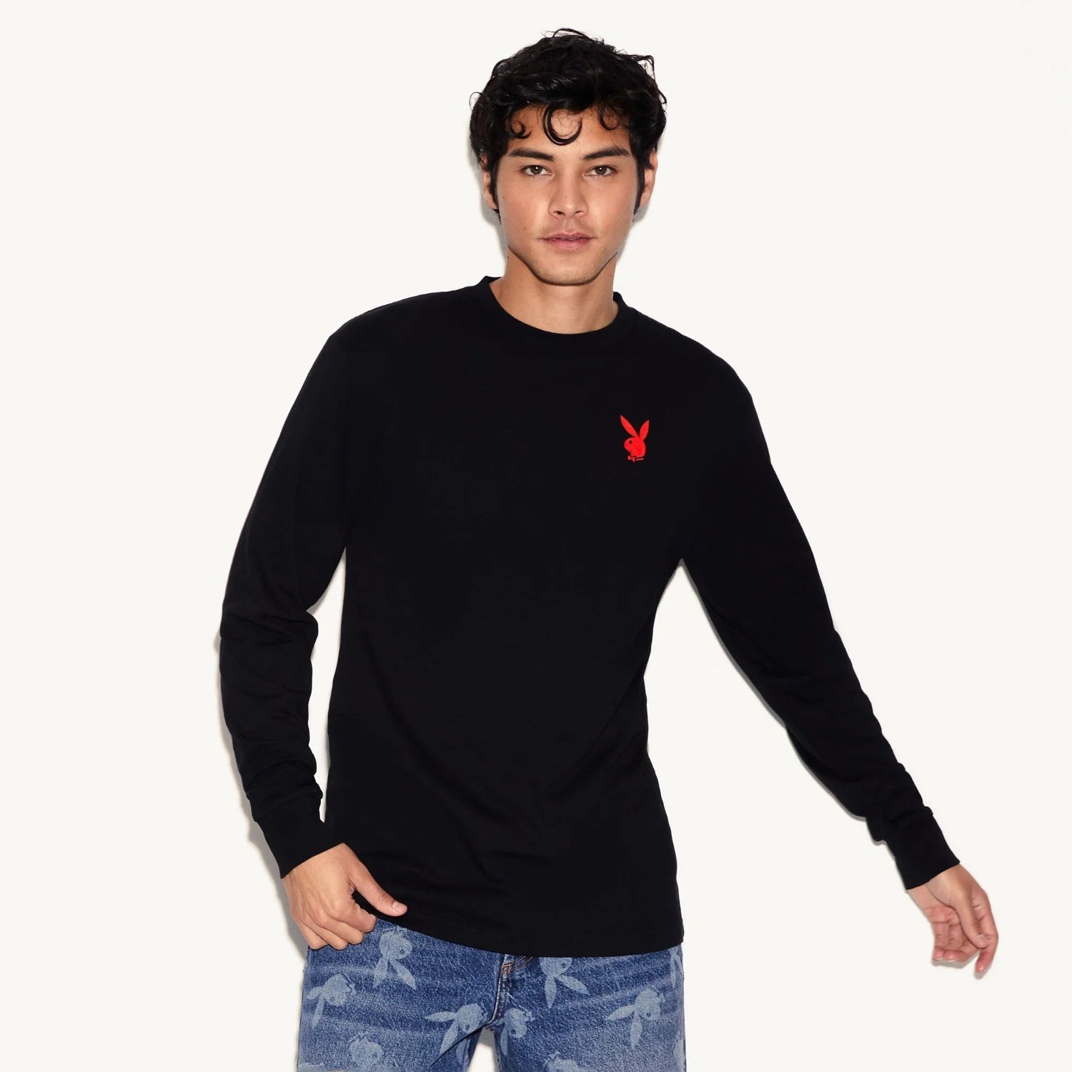 Man wearing black long sleeve t-shirt with red bunny logo and blue jeans with bunny print.