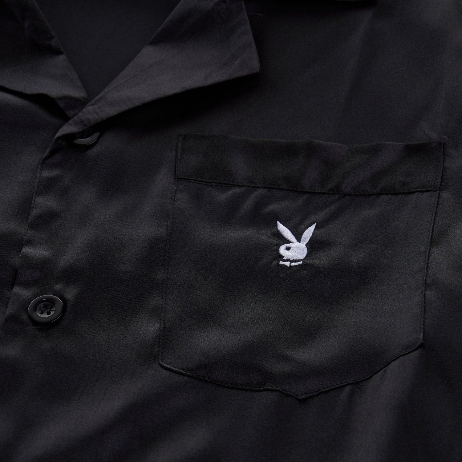 Black satin shirt with button closure and embroidered white bunny logo on chest pocket