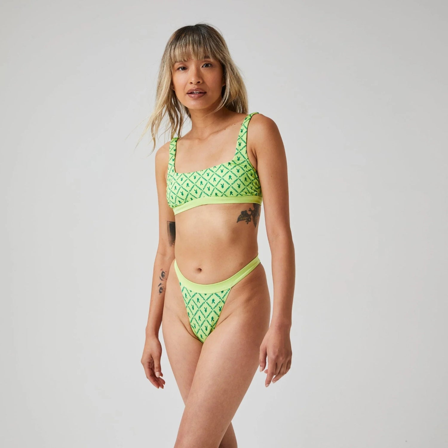 Woman modeling neon green scoop bikini set with geometric pattern on white background