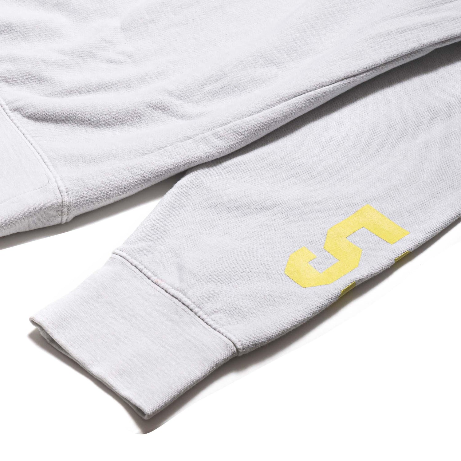 Light gray crewneck sweatshirt sleeve with yellow number 5 graphic detail