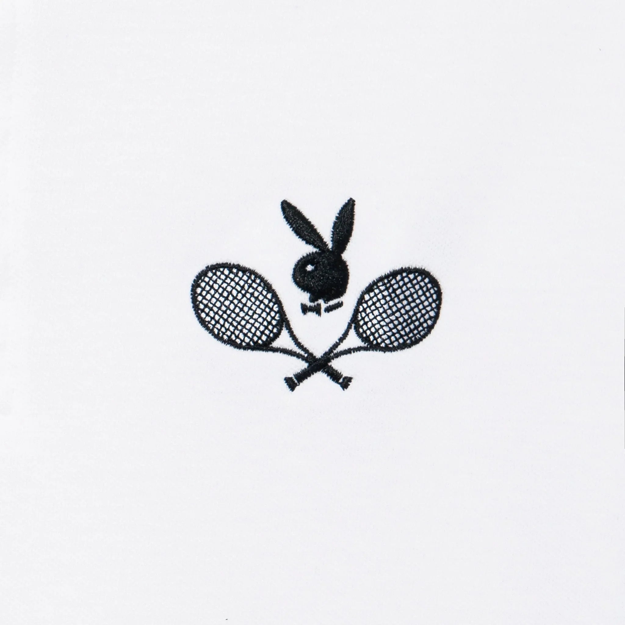 Black embroidered rabbit head and crossed tennis racquets on white polo shirt fabric