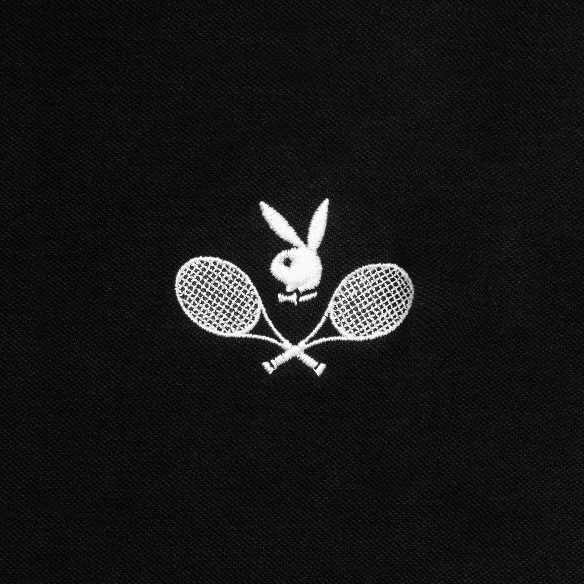 Black polo shirt with white embroidered bunny logo above crossed tennis rackets