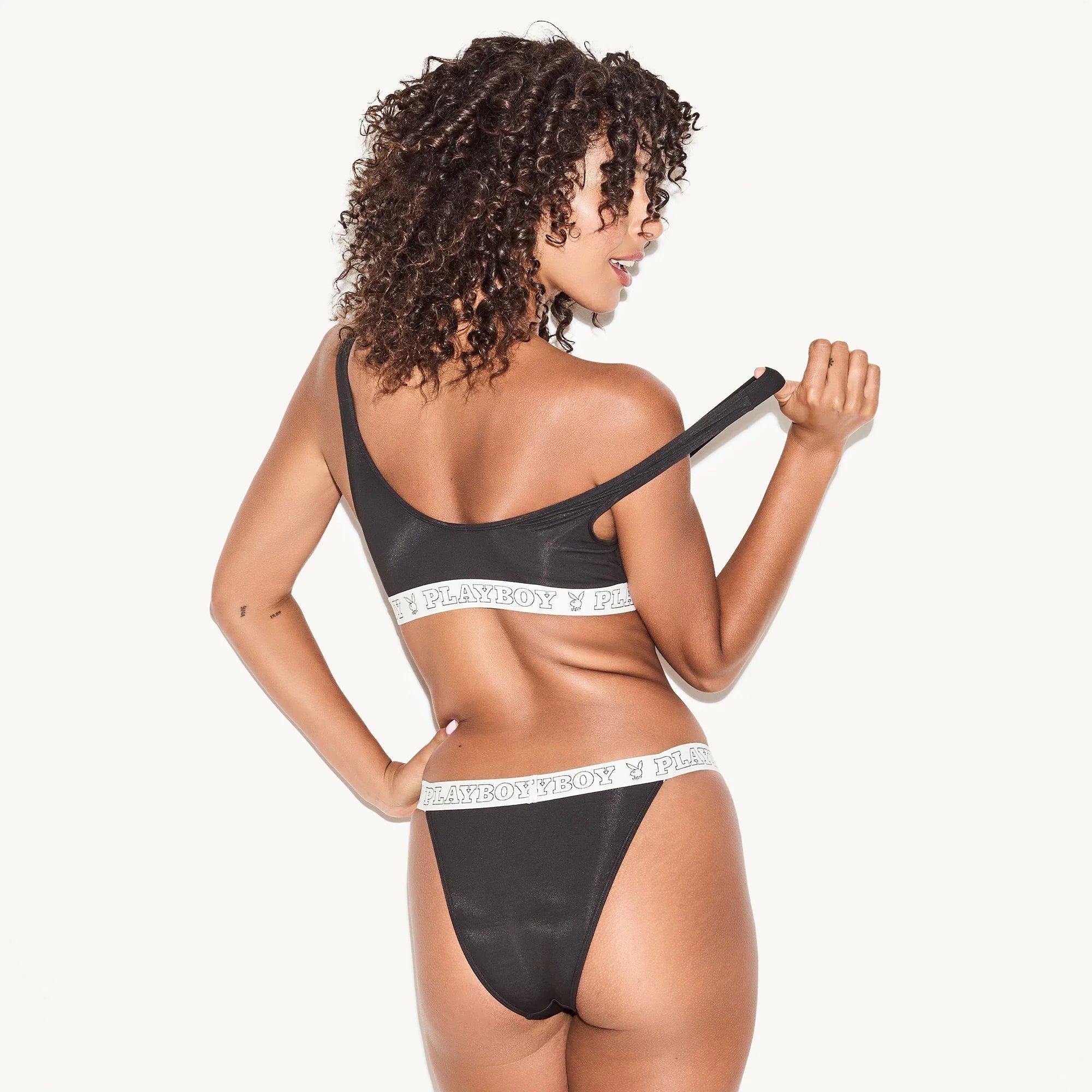 Woman modeling black cheeky bikini set with elastic waistband and bold logo detailing