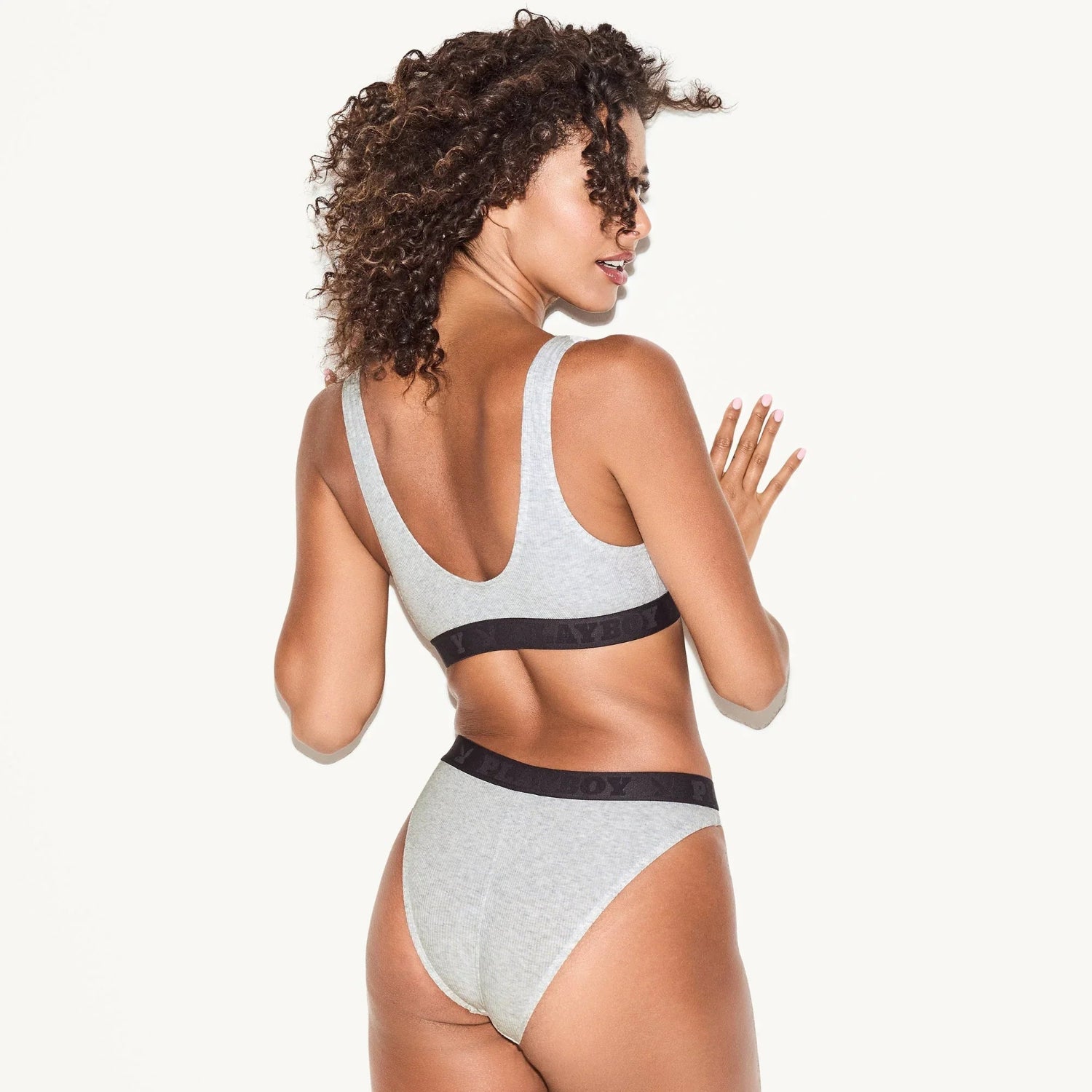 Woman wearing light grey ribbed brief underwear and matching bra with black waistband.