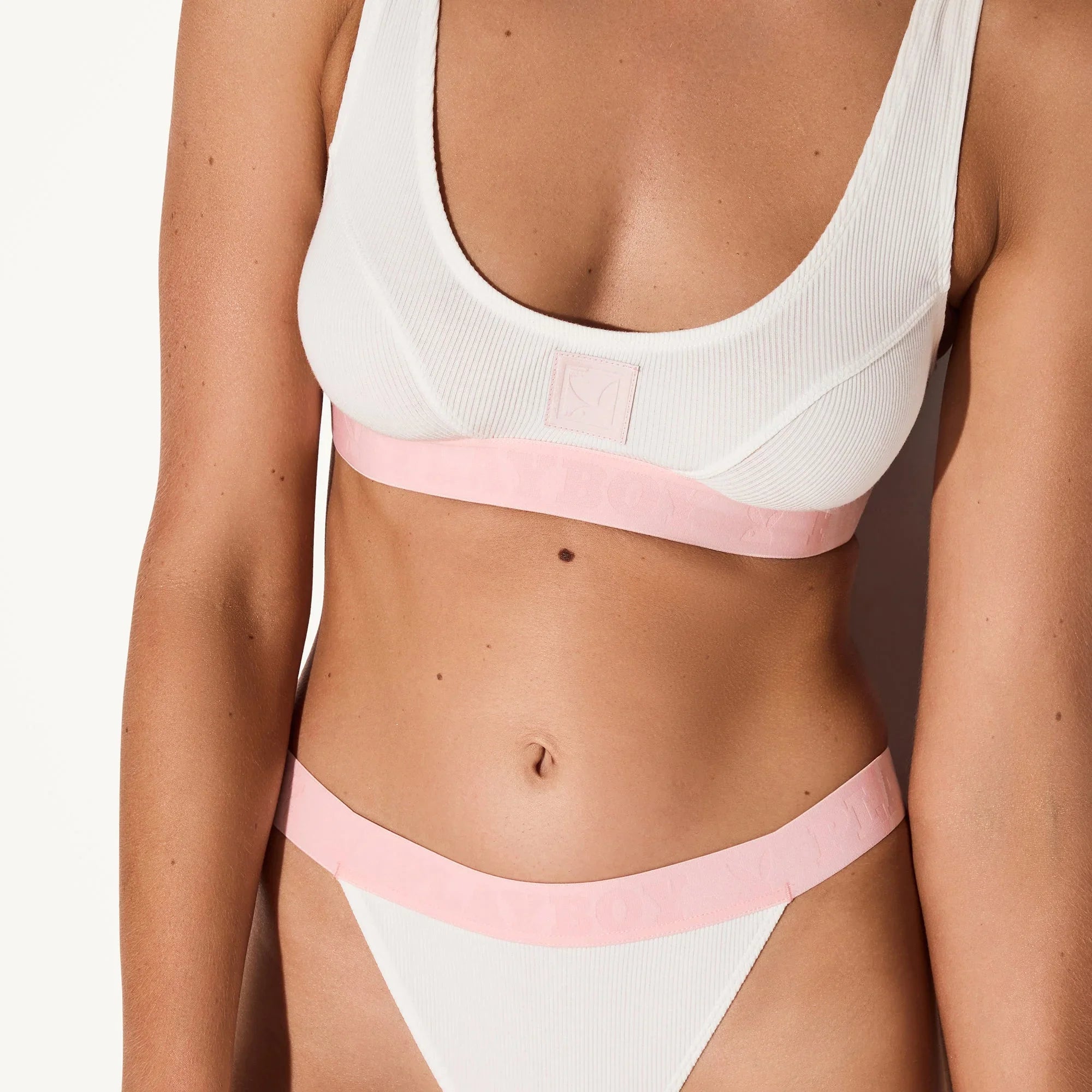 White ribbed scoop neck bra and matching underwear with pink elastic band on model