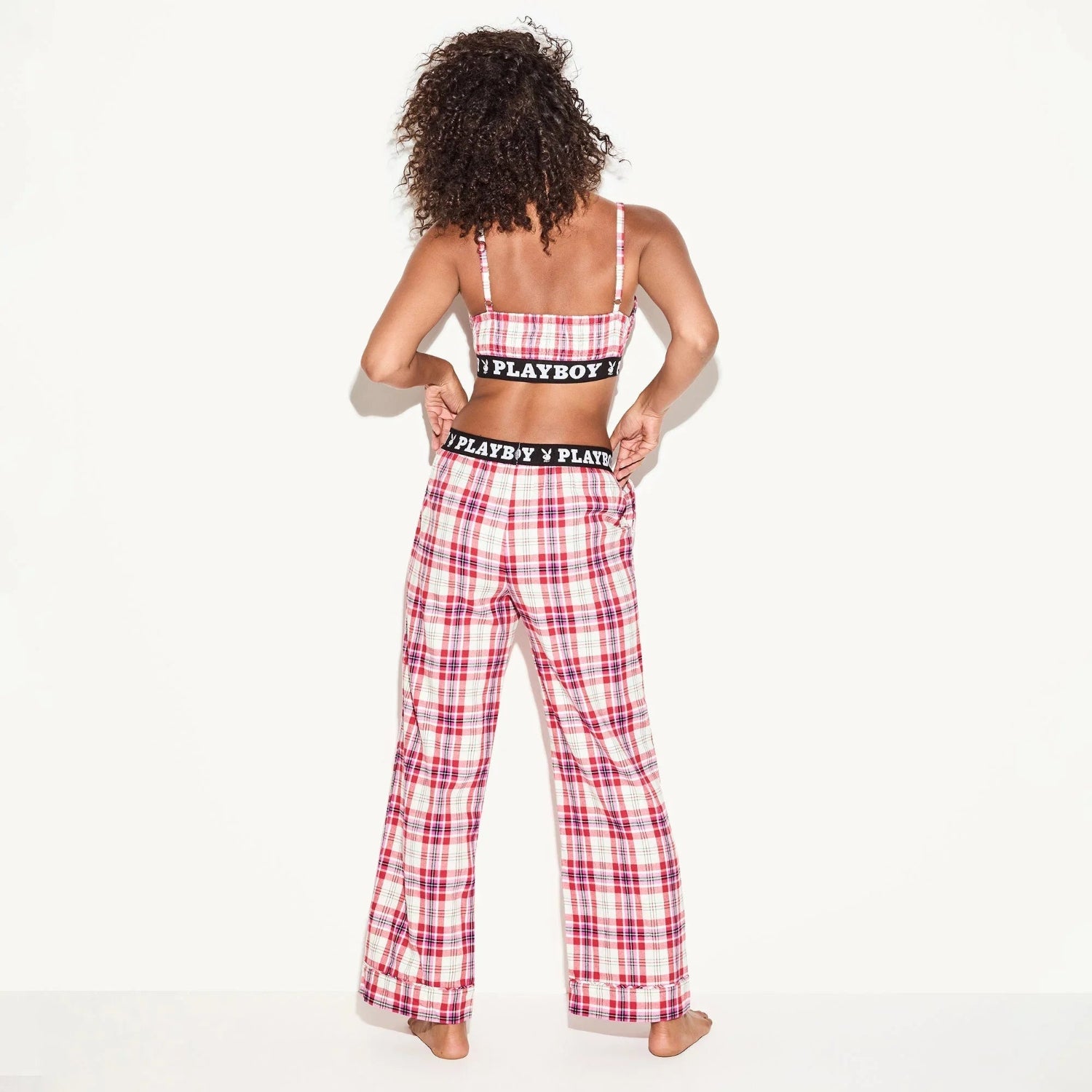 Woman in plaid flannel pajama pants and matching bralette, back view, elastic logo band
