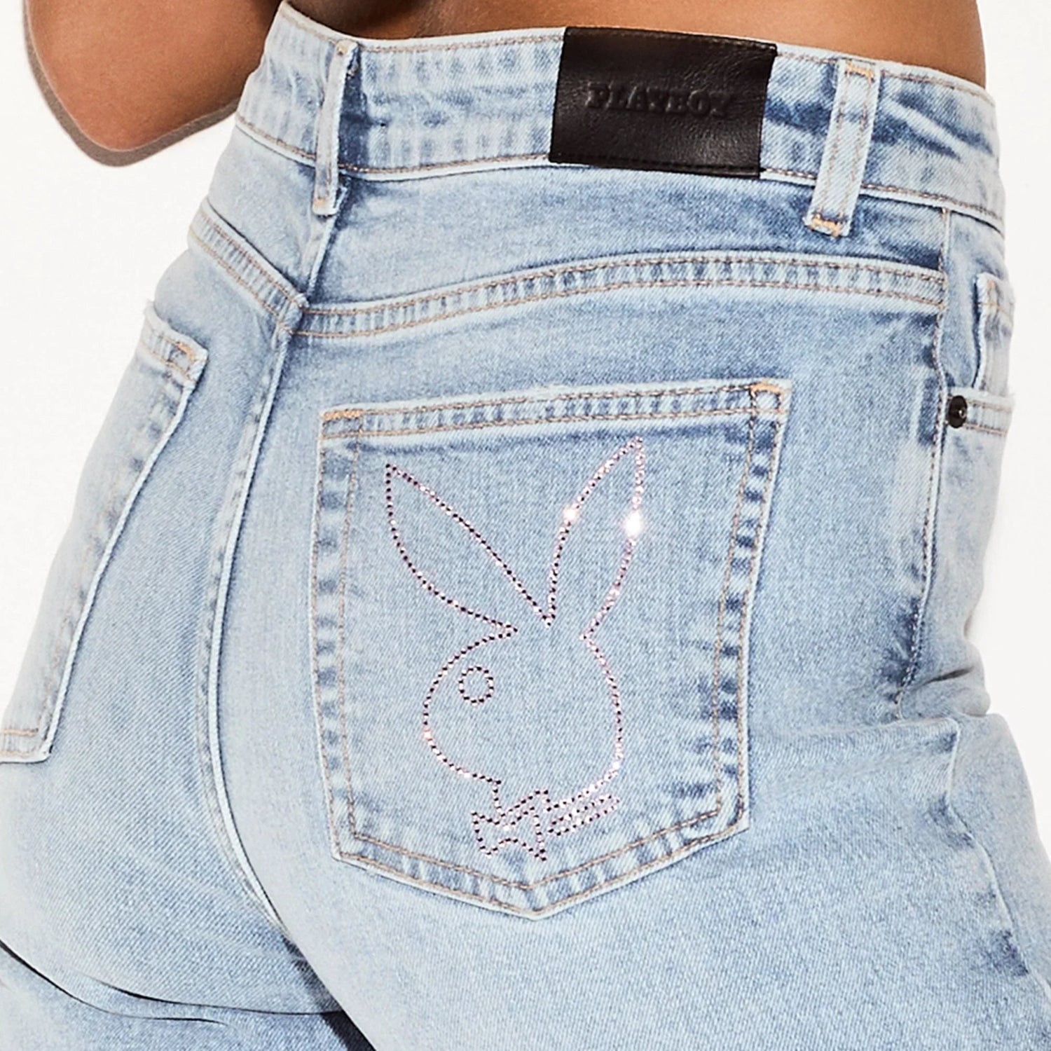 Light wash flare jeans with jeweled bunny logo on back pocket, close-up view