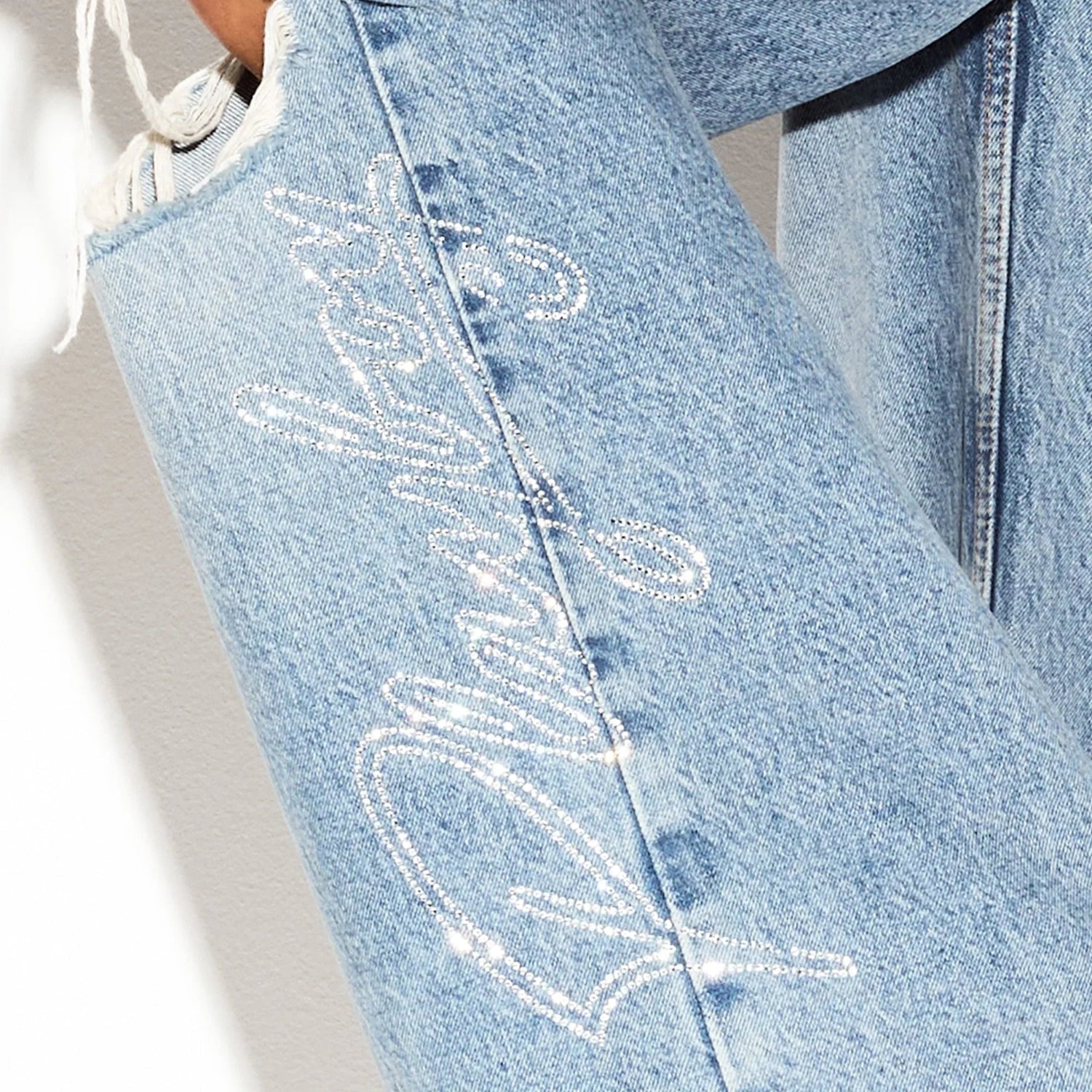 Light wash ripped skater jeans with rhinestone script detail on the leg
