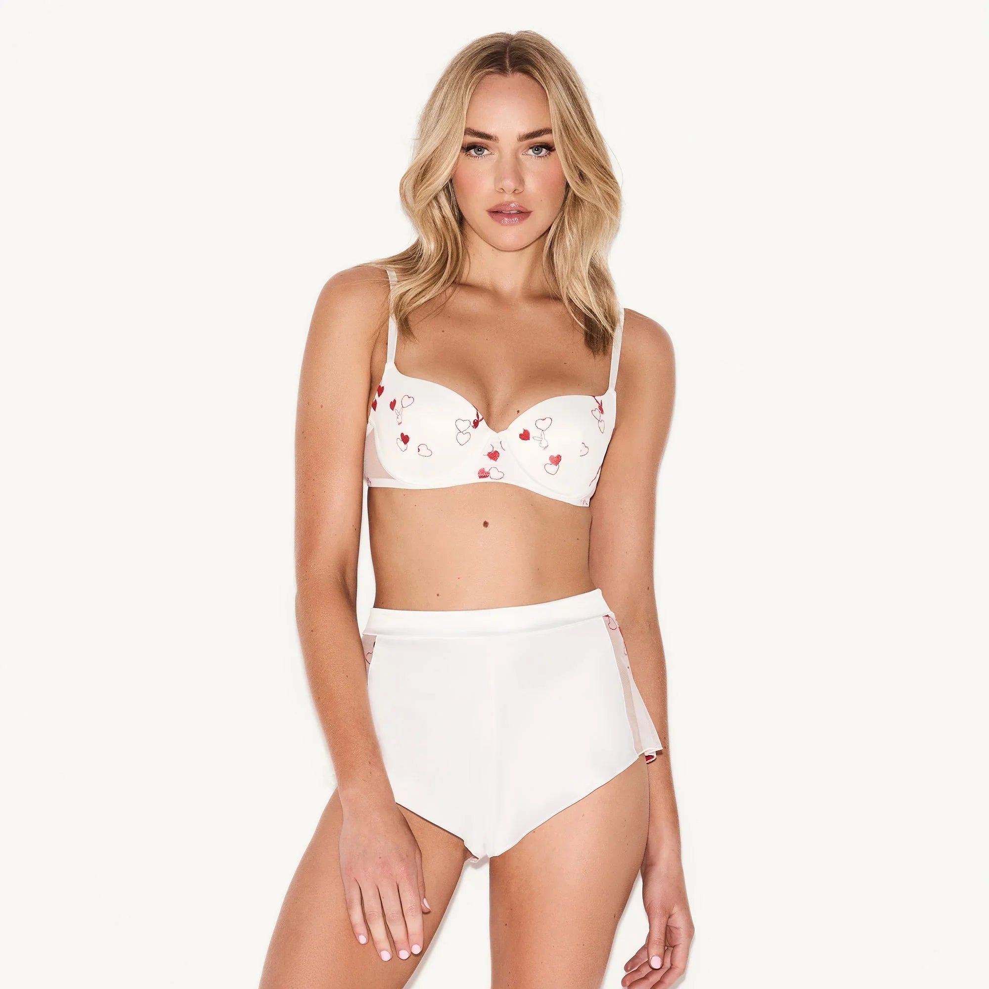 Woman modeling white push-up plunge bra with small red heart pattern and matching high-waist bottoms