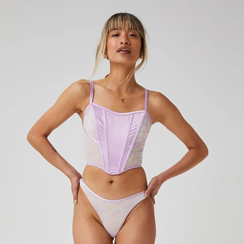 Woman modeling lilac corset top and matching lingerie panties with script detail