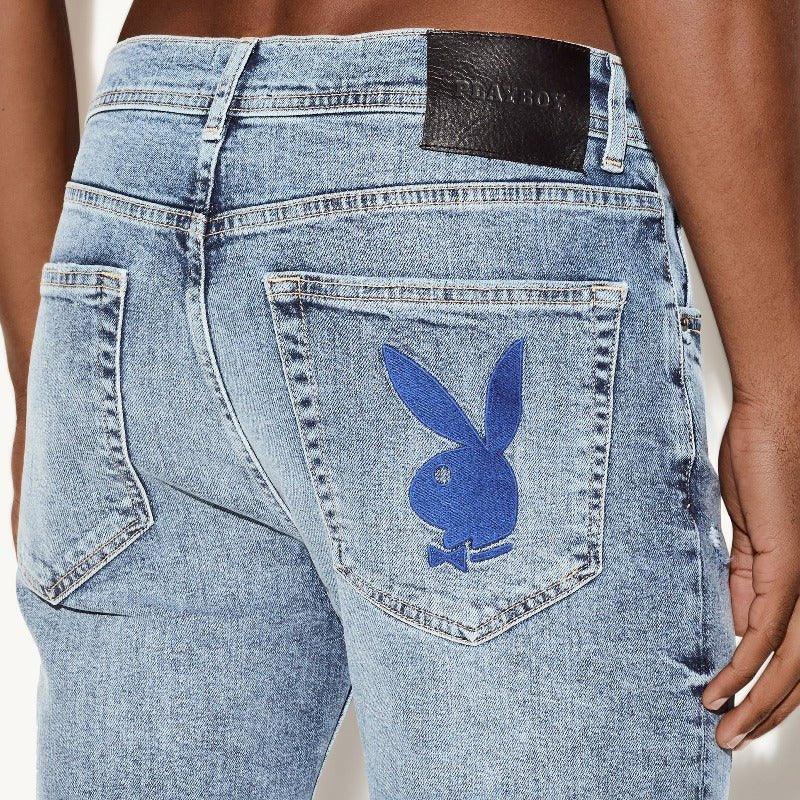 Light wash skinny jeans with blue bunny logo patch on back pocket, model shown from behind