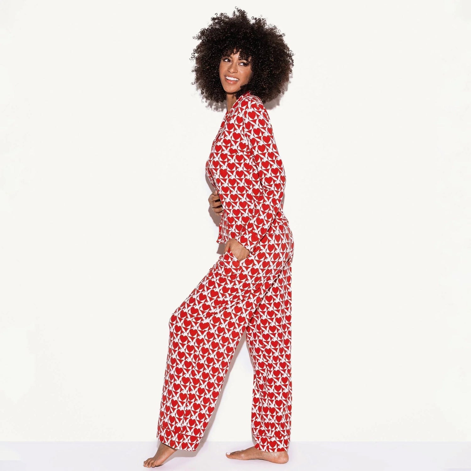 Woman modeling red and white long-sleeve pajama set with bold heart pattern