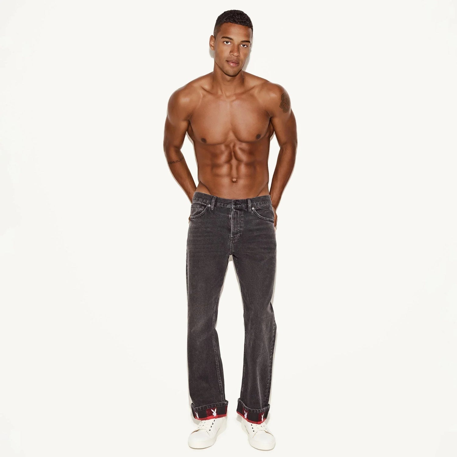 Male model wearing straight leg vintage black wash jeans with white sneakers on white background