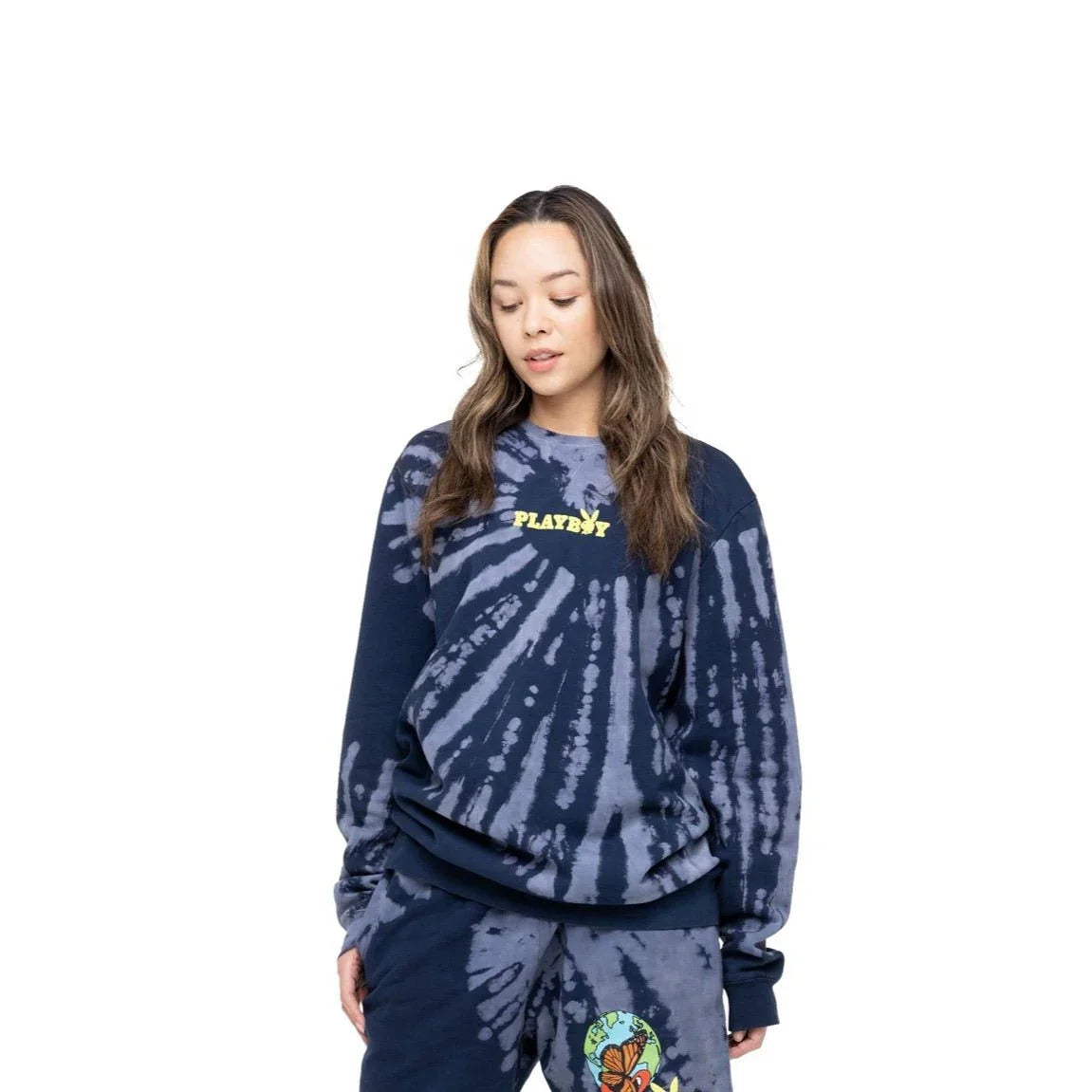 Woman wearing navy blue tie-dye sweatshirt with yellow logo and matching sweatpants