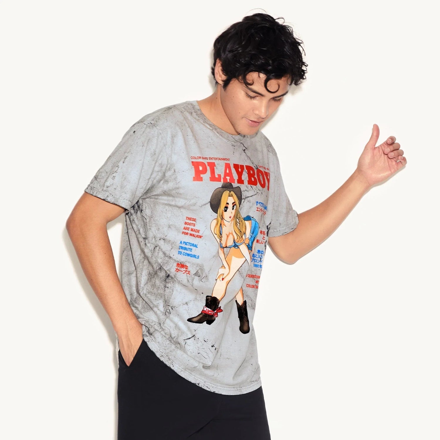 Man wearing grey graphic tee with cartoon cowgirl and red PLAYBOY text, casual streetwear