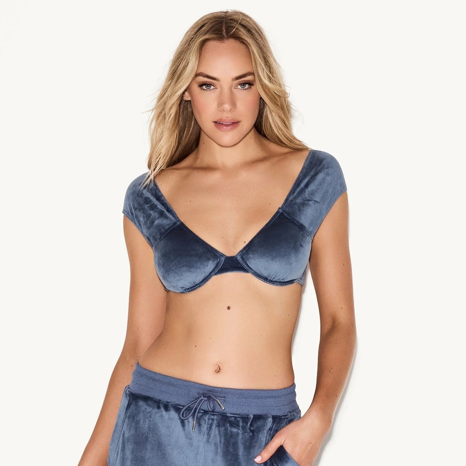 Woman wearing blue velour underwire cap sleeve bra and matching lounge pants