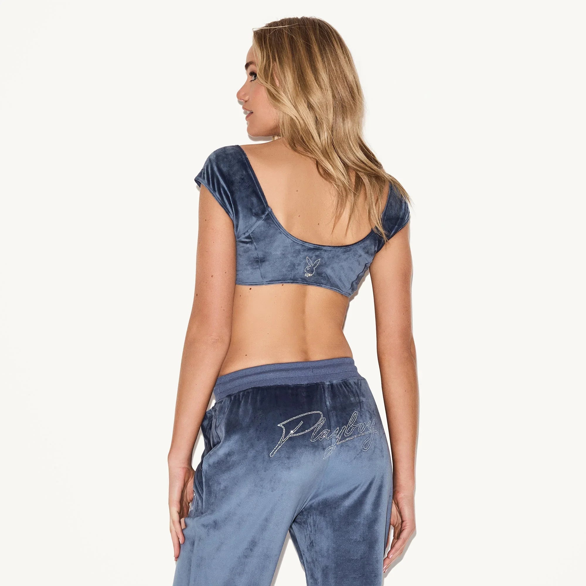 Woman in blue velour cap sleeve bra top and matching pants with bunny logo embroidery