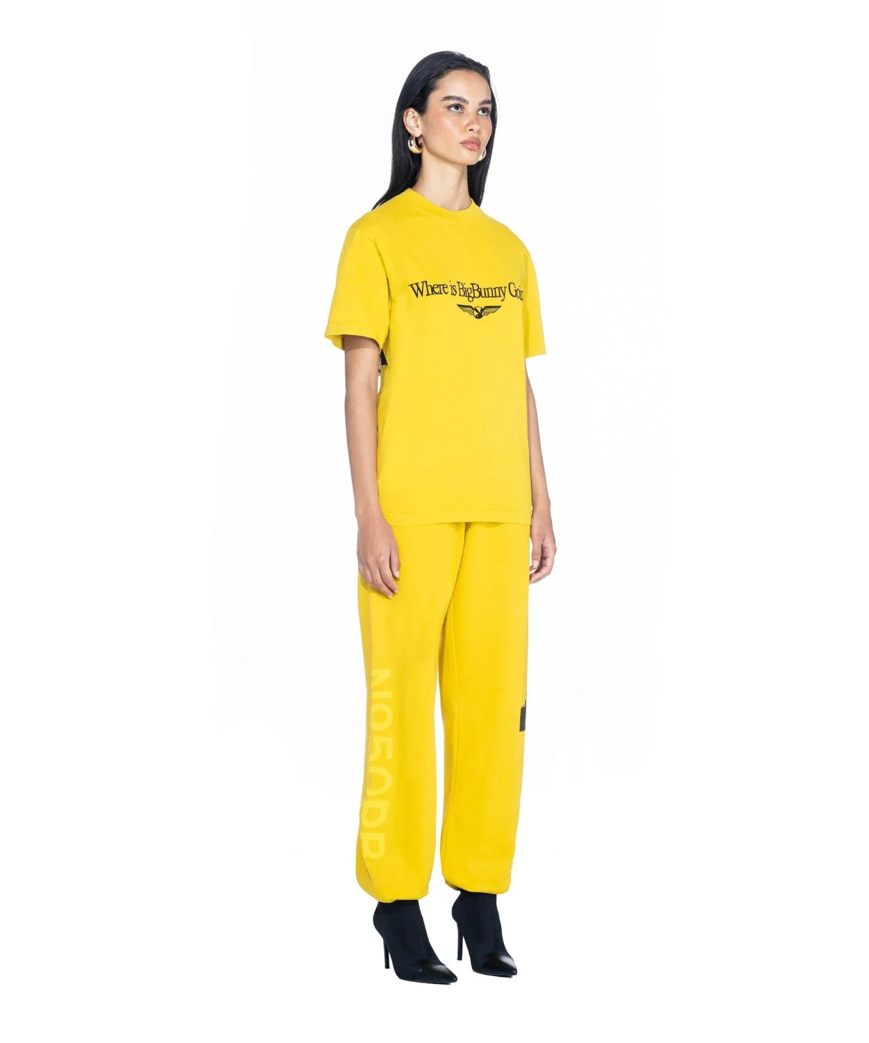 Woman in yellow graphic t-shirt and matching pants, standing against white background