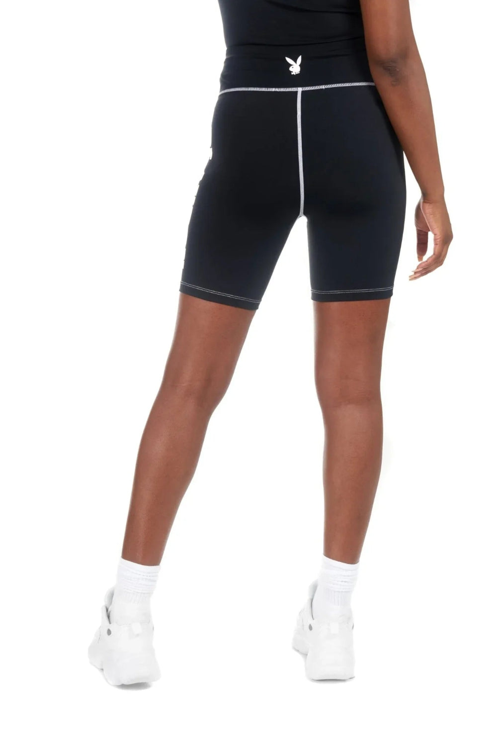 Woman wearing black active bike shorts with white stitching and a small bunny logo on waistband