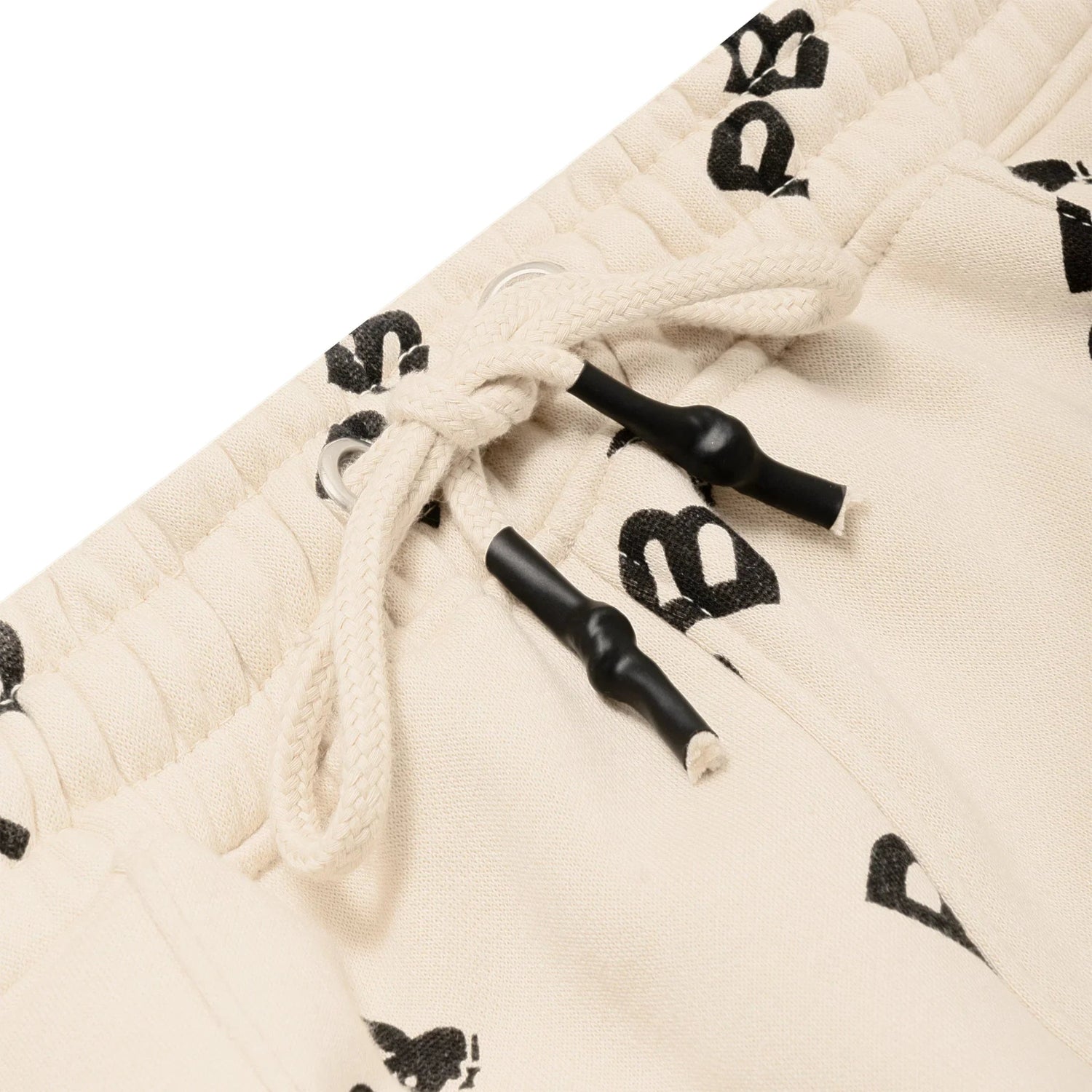Close-up of beige women's joggers with black all-over graphic print and drawstring waistband