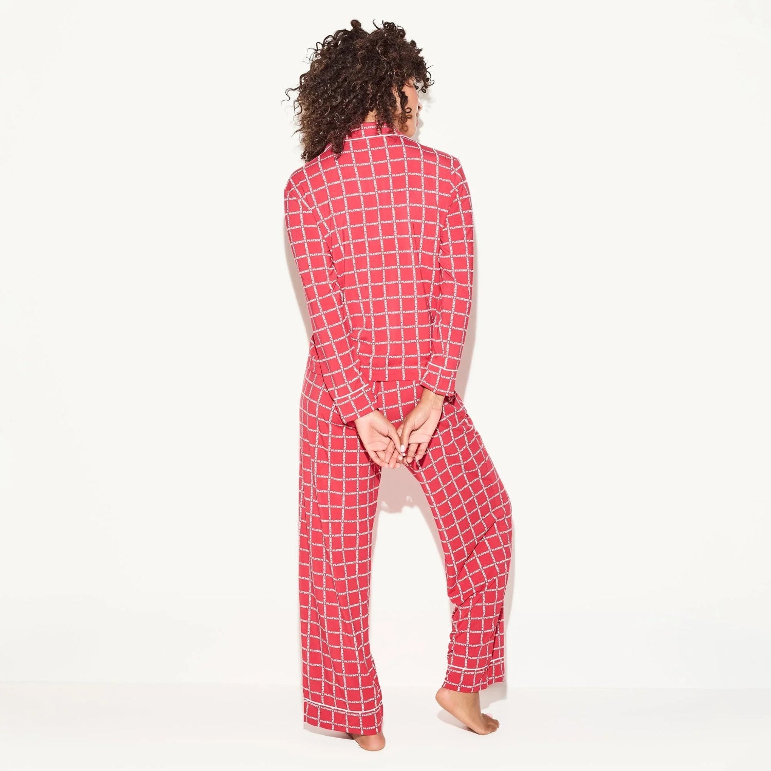 Woman wearing red checkered long sleeve pajama set, standing barefoot, back view